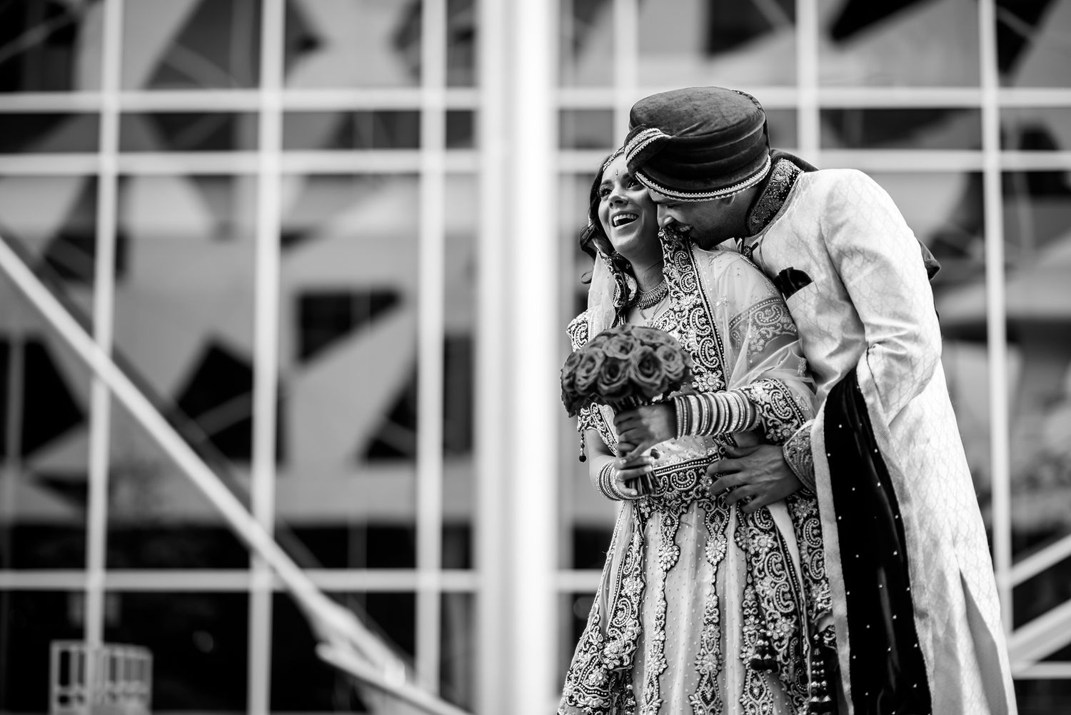 A black and white intimate moment captured at a traditional Indian wedding celebration with decorative outfits and jewelry.