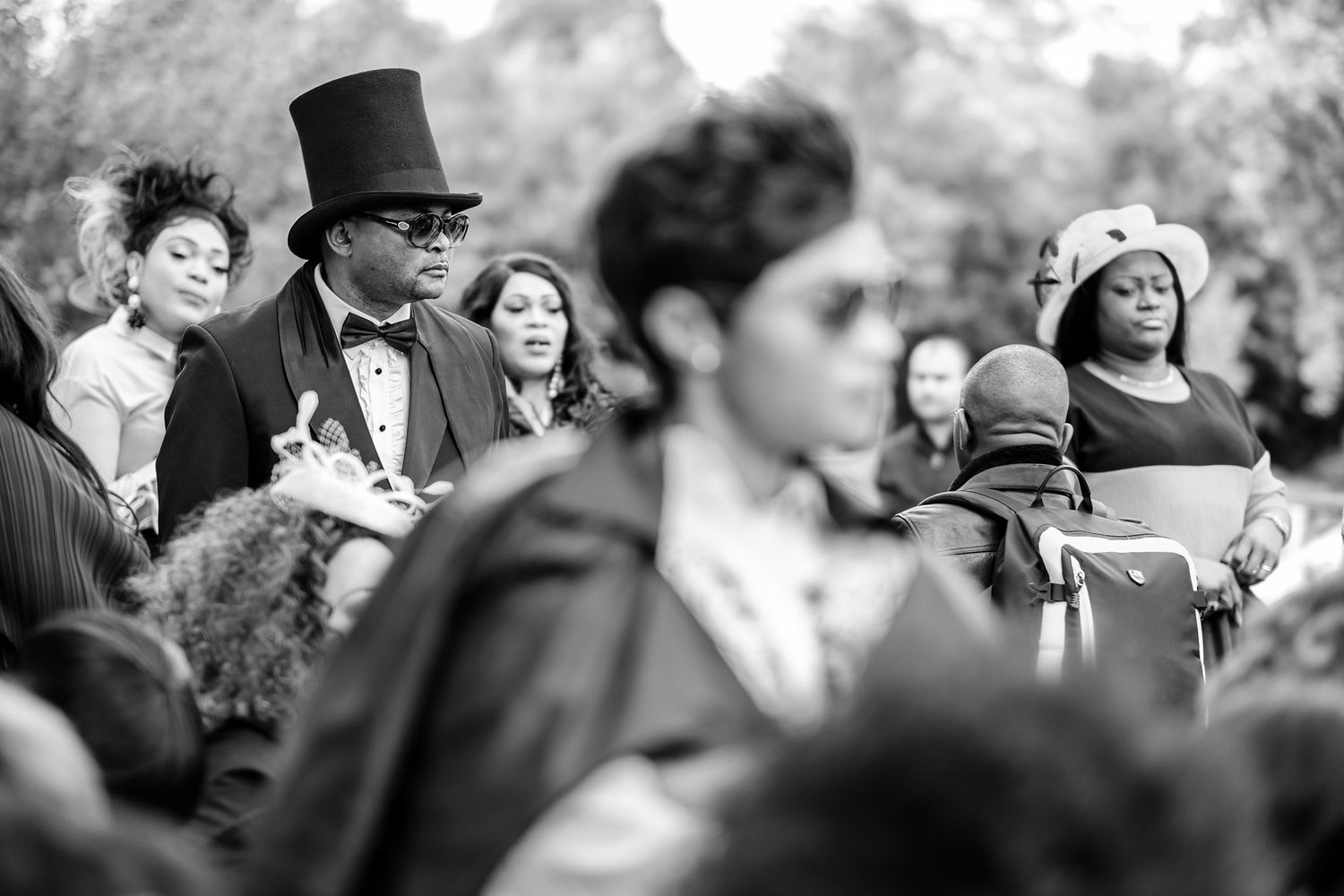 Guests at an outdoor wedding ceremony showing emotional reactions in black and white.