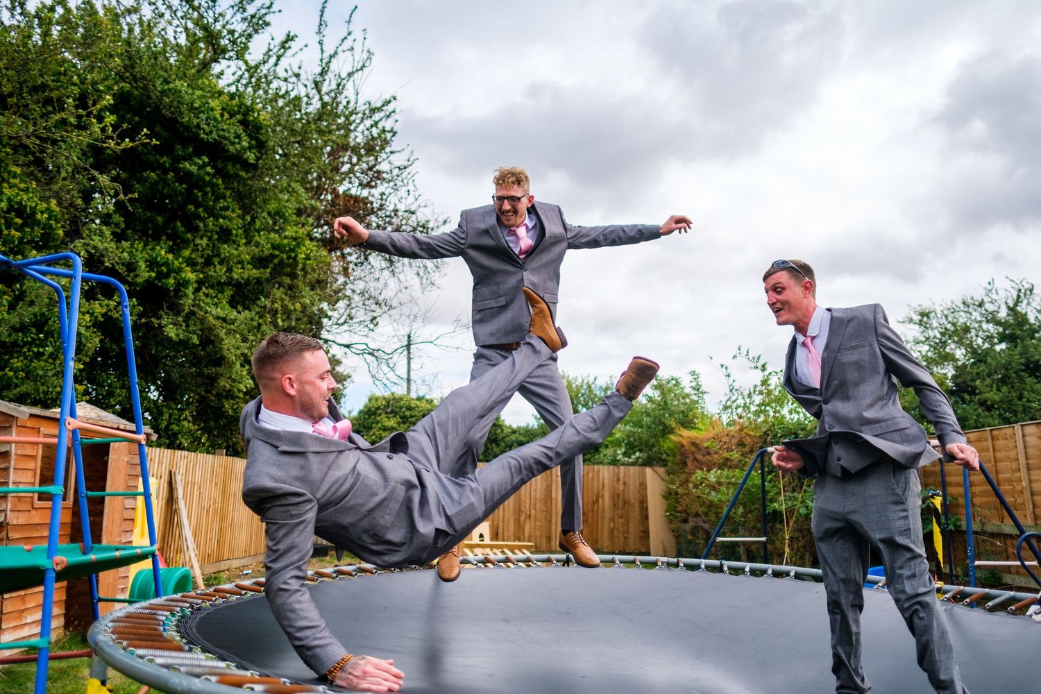 A sequence of playful jumping poses on a backyard trampoline with grey skies in the background.