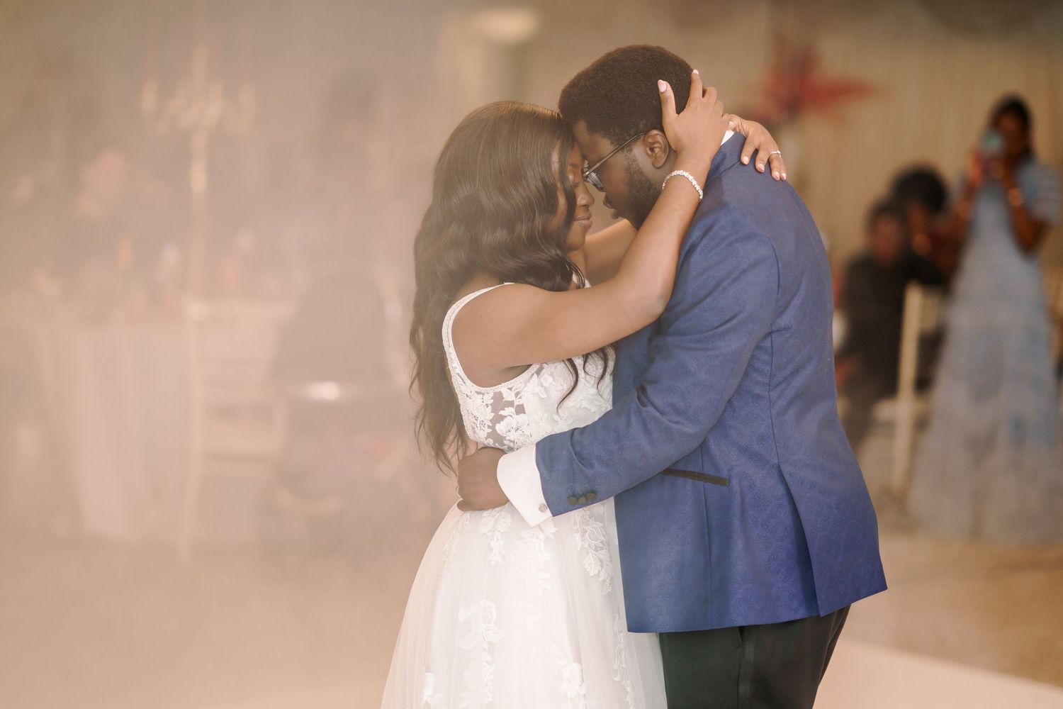 Romantic first dance moment between newlyweds in an elegantly lit reception venue.