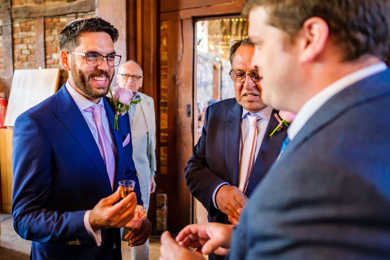 Guests share a lighthearted moment during a wedding celebration in a rustic wooden venue.