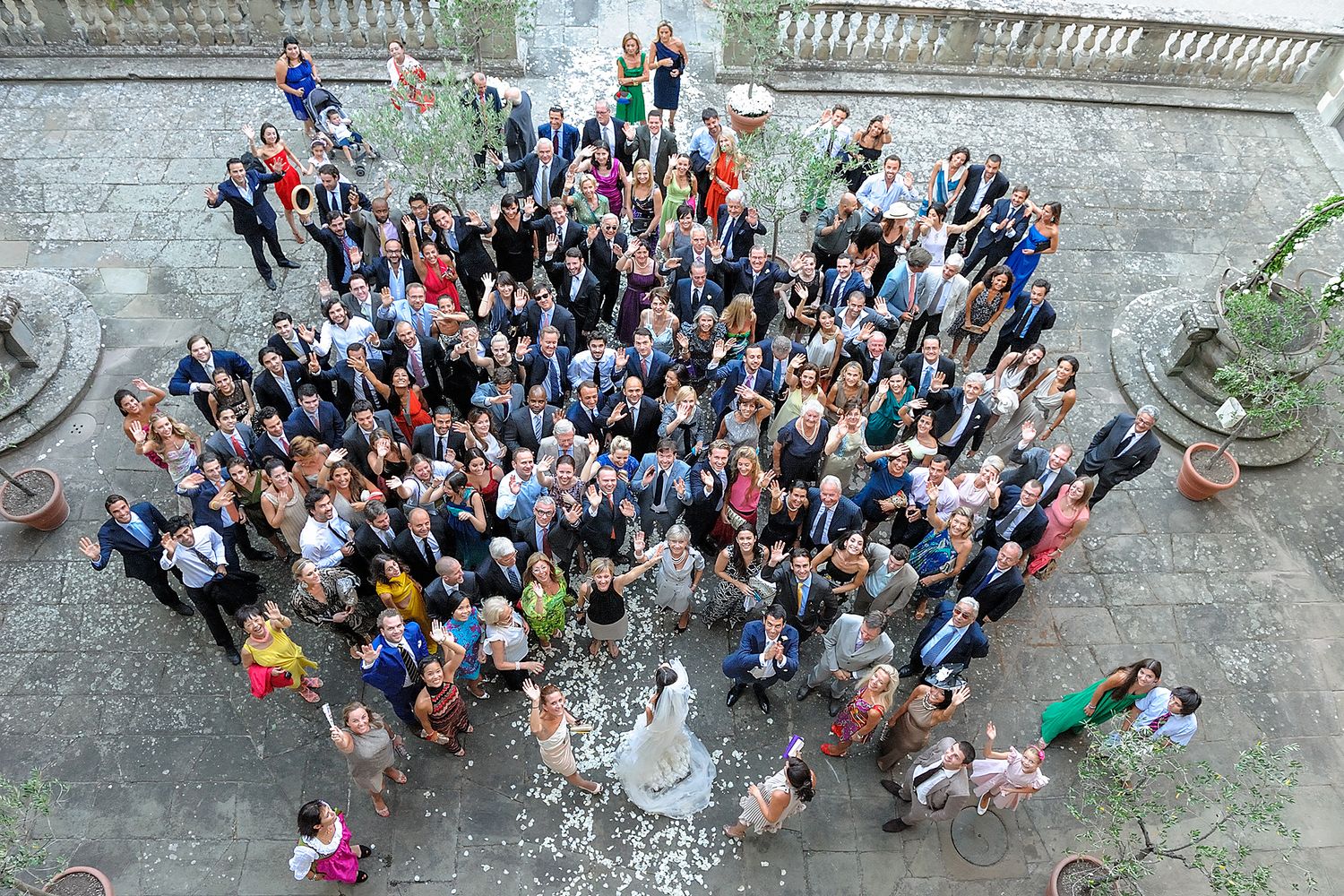 Large group of wedding guests gathered for an outdoor photo on stone steps.
