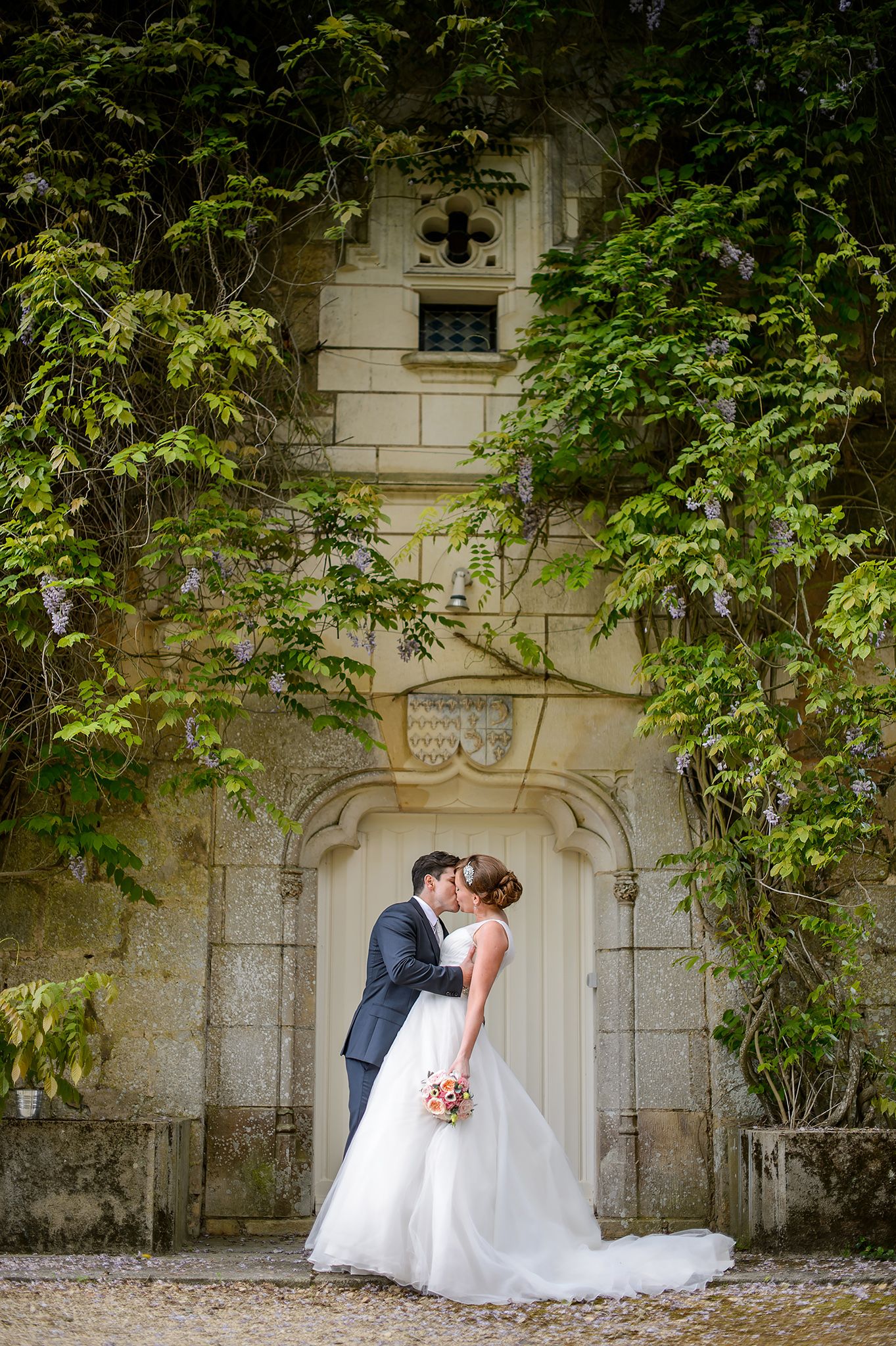 Stone wall with ornate architectural details creates romantic backdrop for wedding photos.