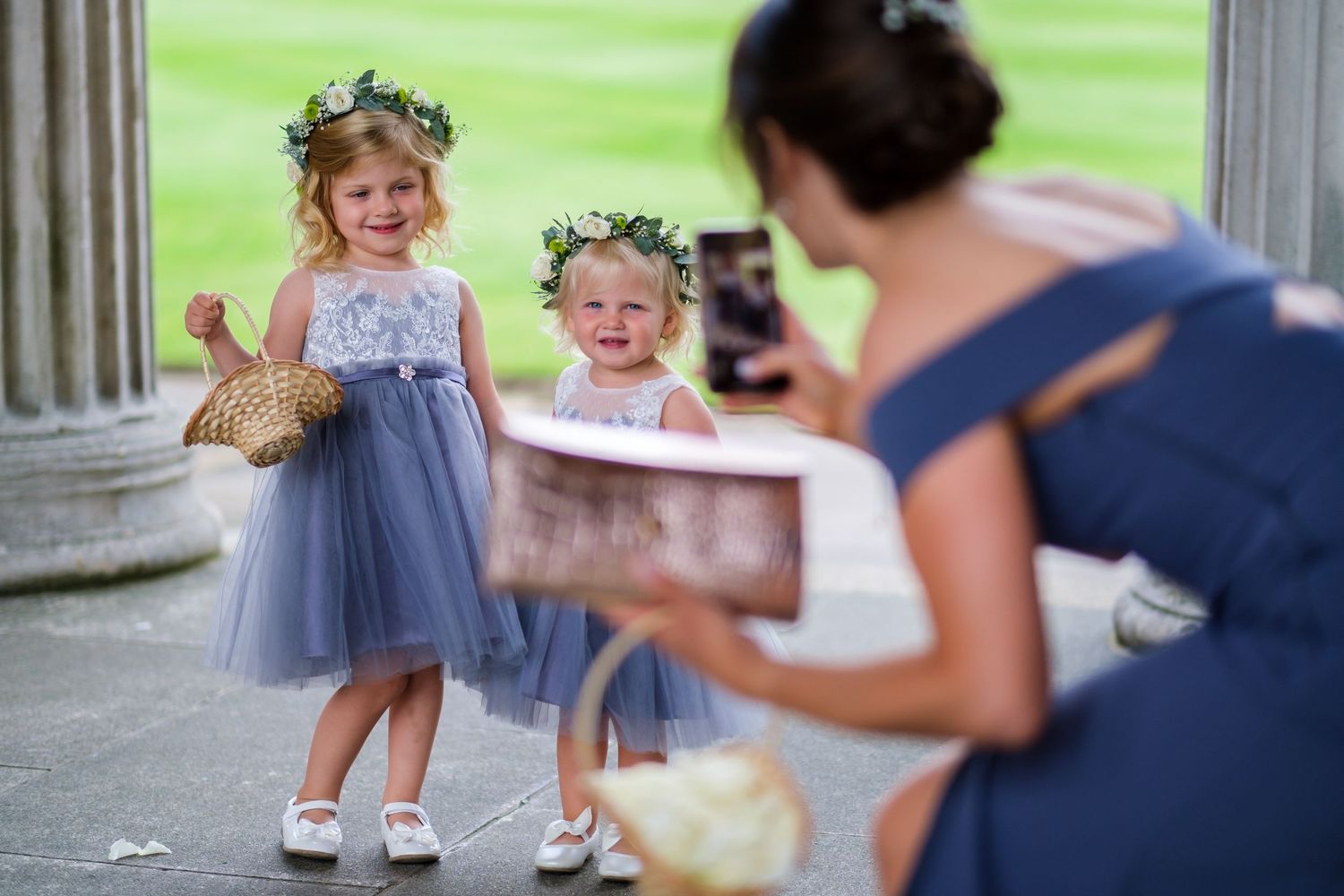 Young attendants in formal wear walk down church aisle during wedding ceremony.