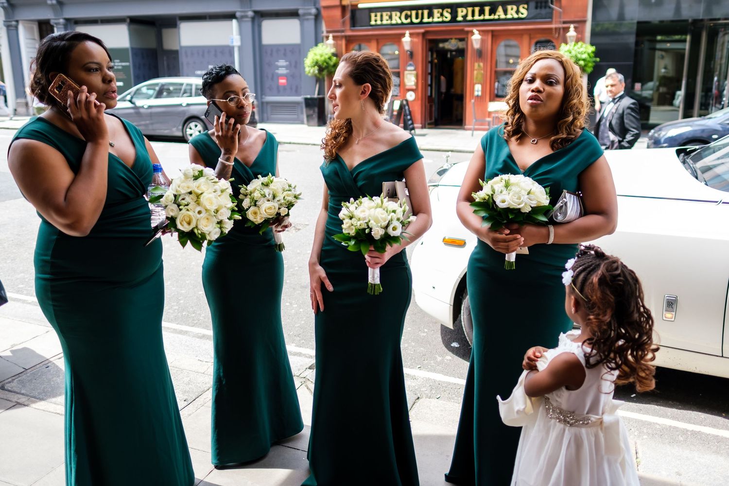Wedding party members in teal dresses stand together in an urban setting.