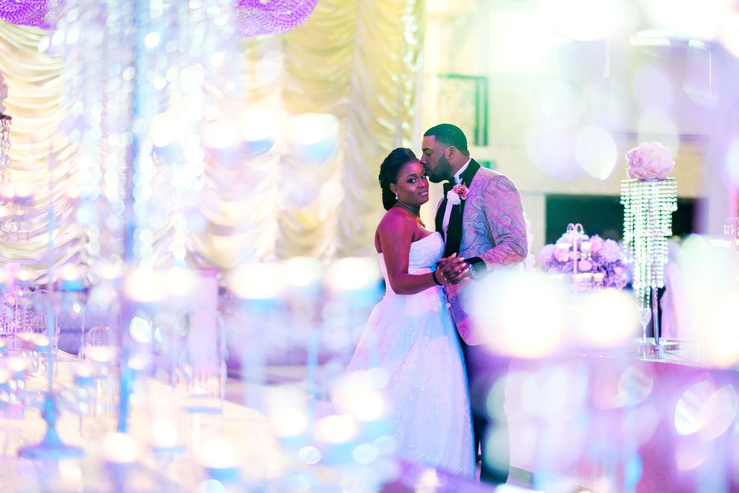 Romantic couple dancing at wedding reception with soft lighting and crystal decorations.