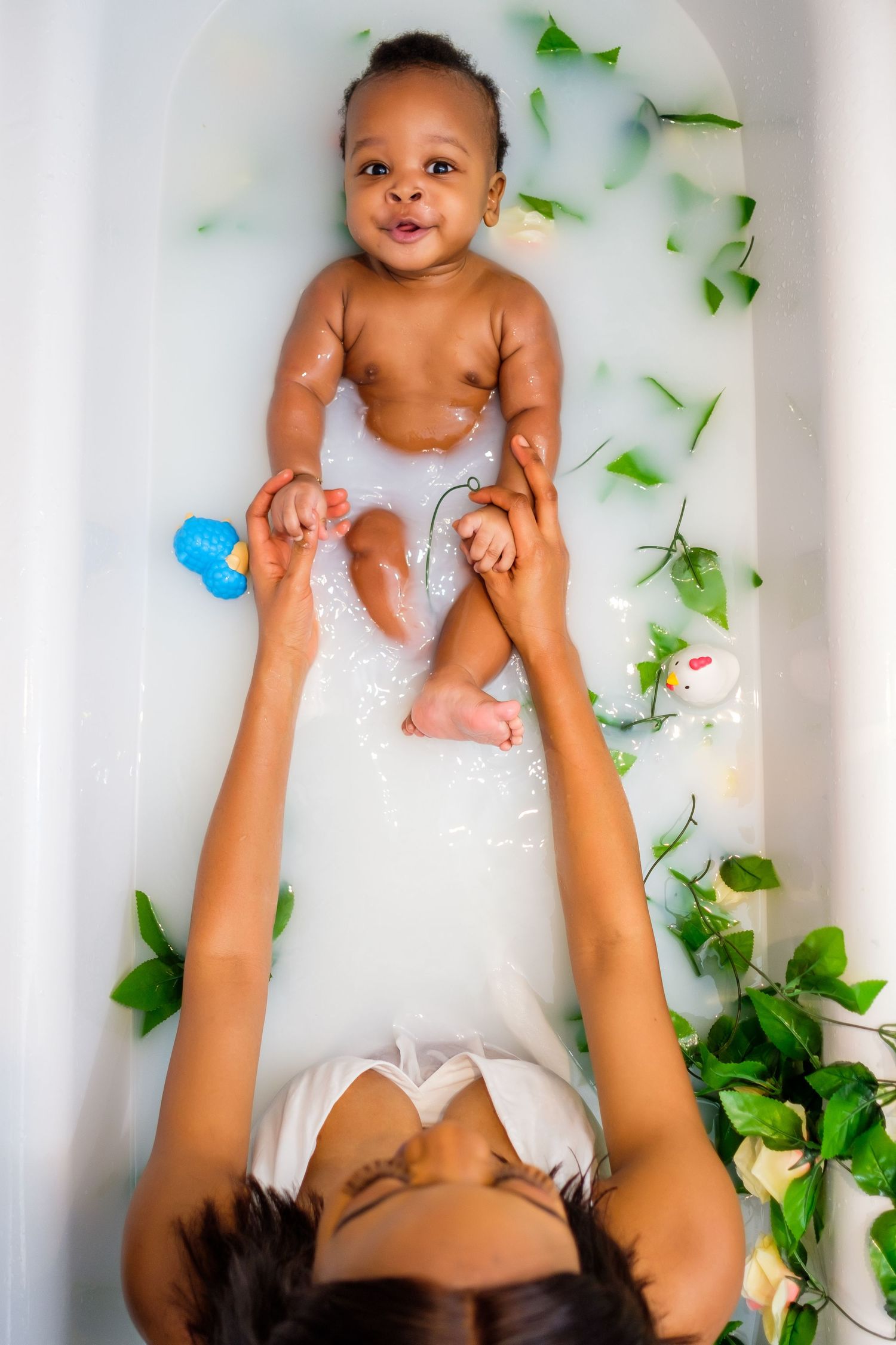 A high-angle view of bathtime with green foliage decorations and bubbles surrounding the tub.