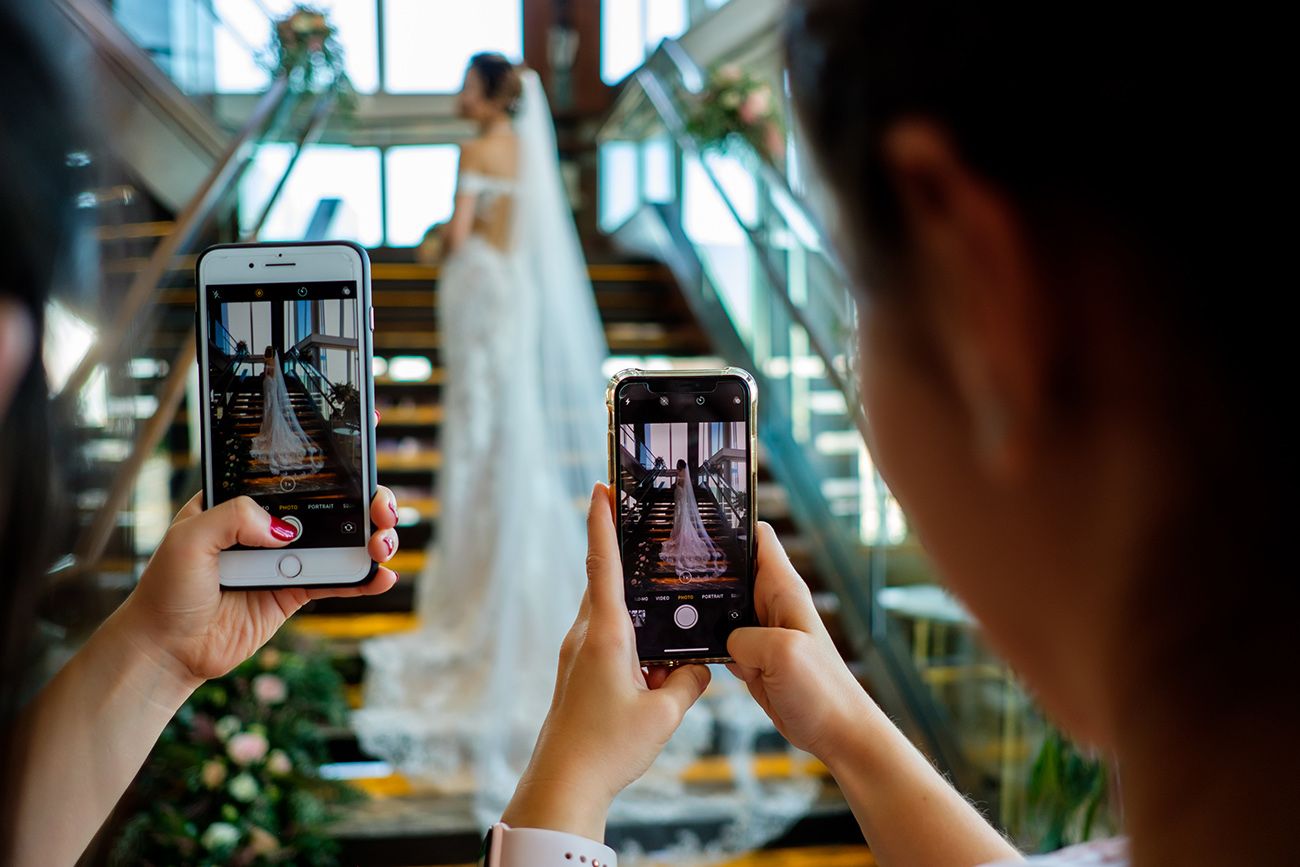 Multiple smartphone screens showing photography in progress through reflective glass.