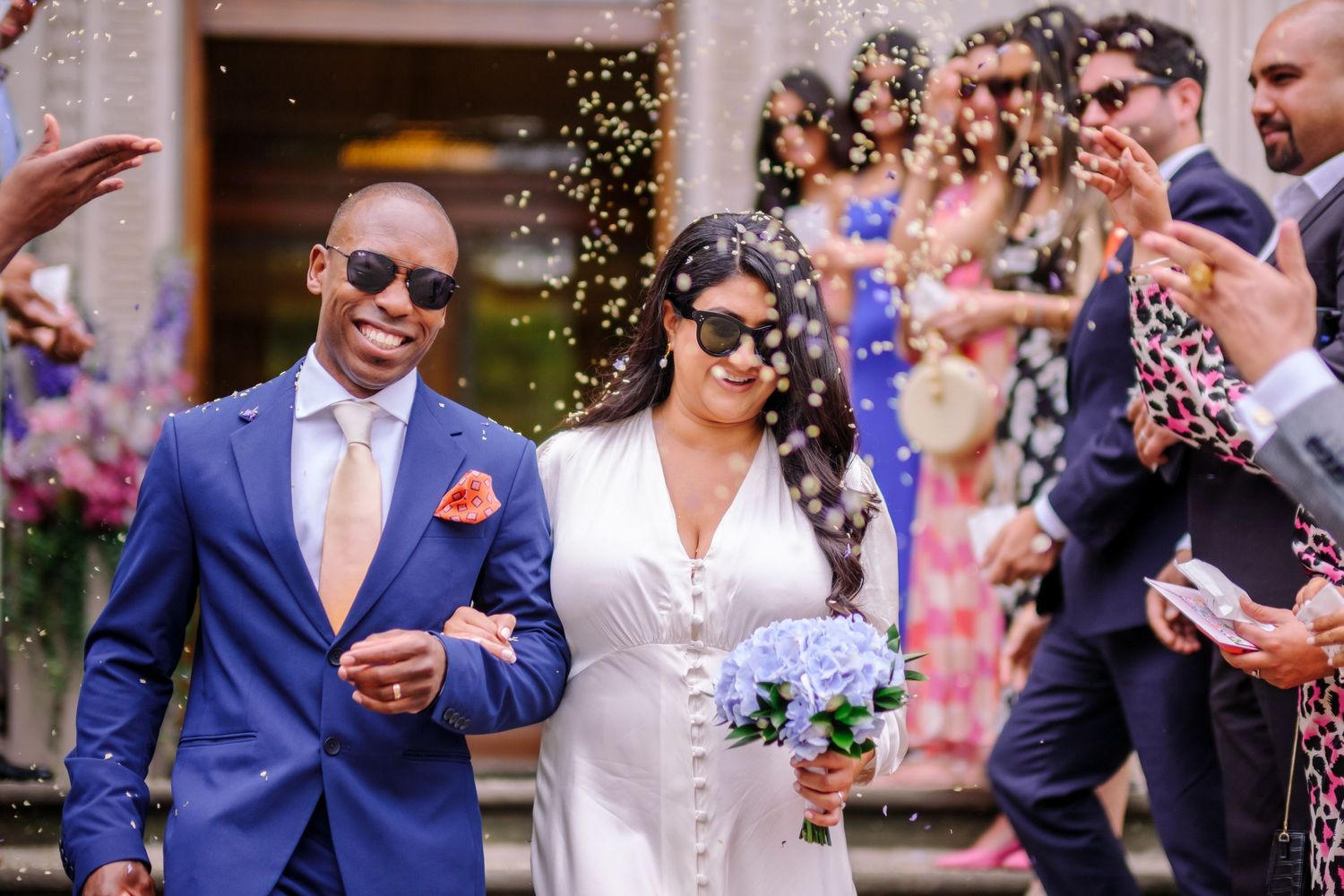 Wedding celebration with guests throwing confetti while a couple shares a joyful moment.