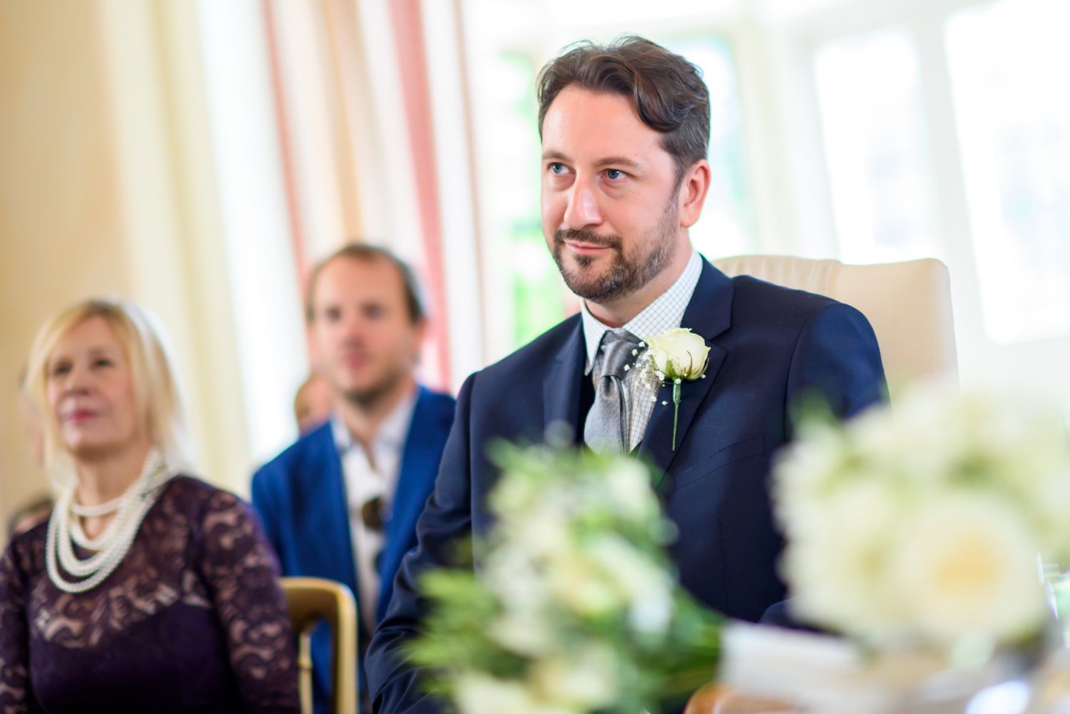 Wedding reception guests share laughter in a bright, formal dining room.