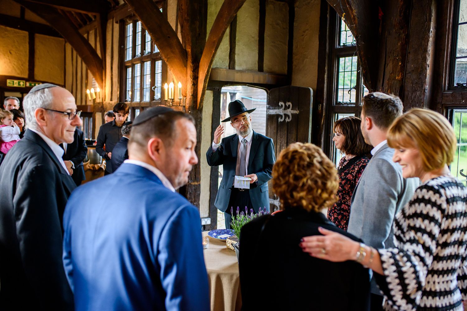 Guests mingling during a wedding reception in a rustic timber-framed venue.
