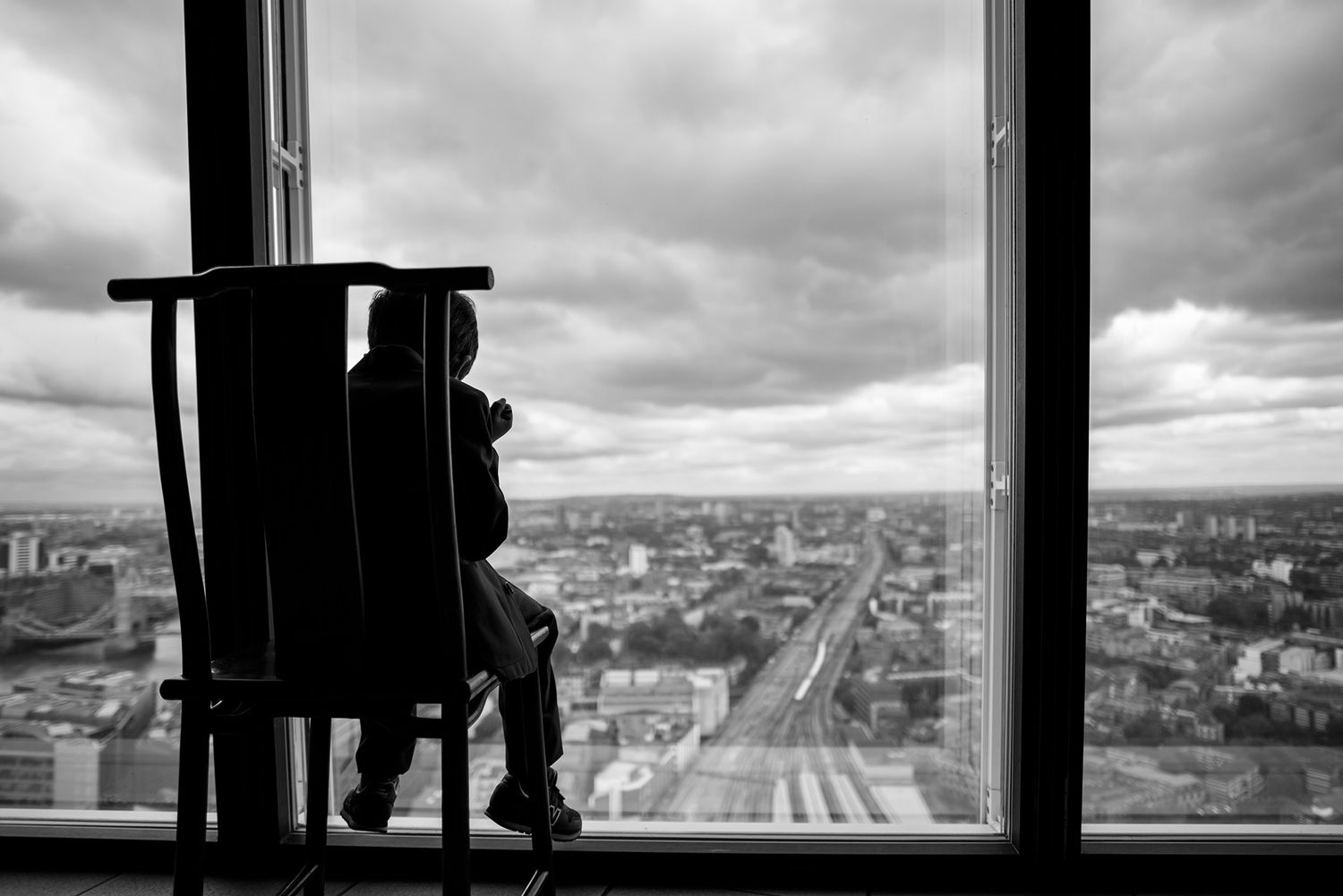 Black and white cityscape view through floor-to-ceiling windows shows urban expanse.