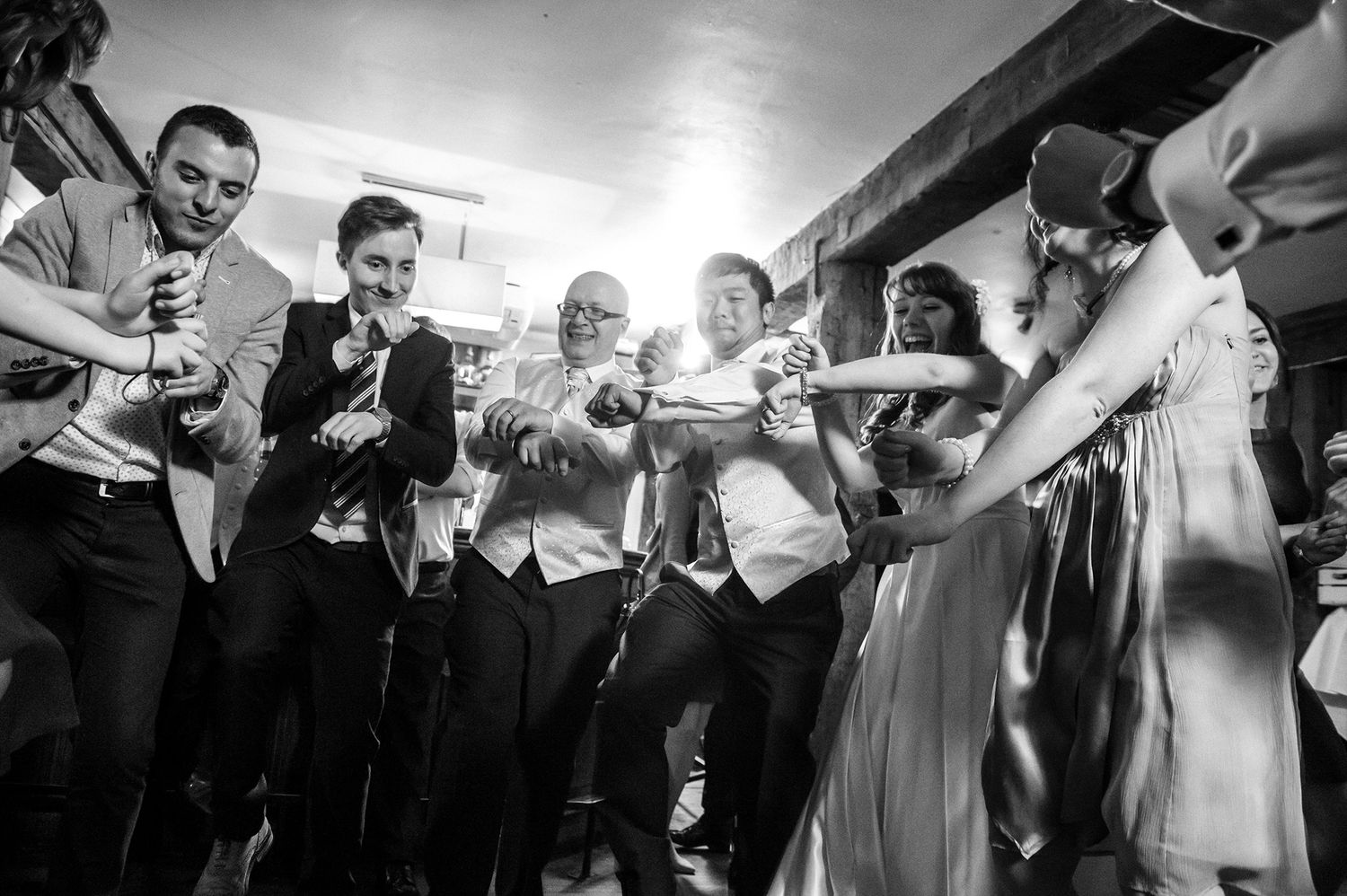 Black and white photo of wedding guests dancing and celebrating together.