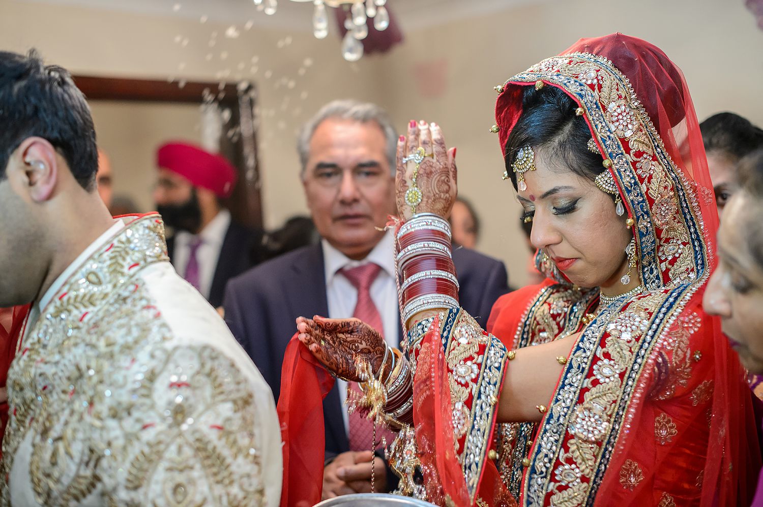Traditional wedding ceremony showing intricate details of South Asian bridal jewelry and attire.