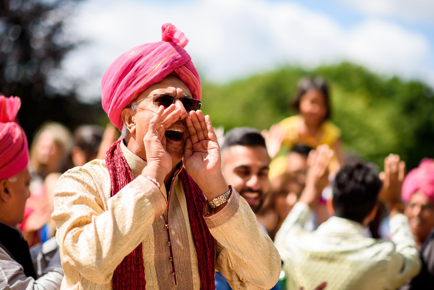 Joyful crowd celebrating at outdoor wedding with traditional decorations and attire.