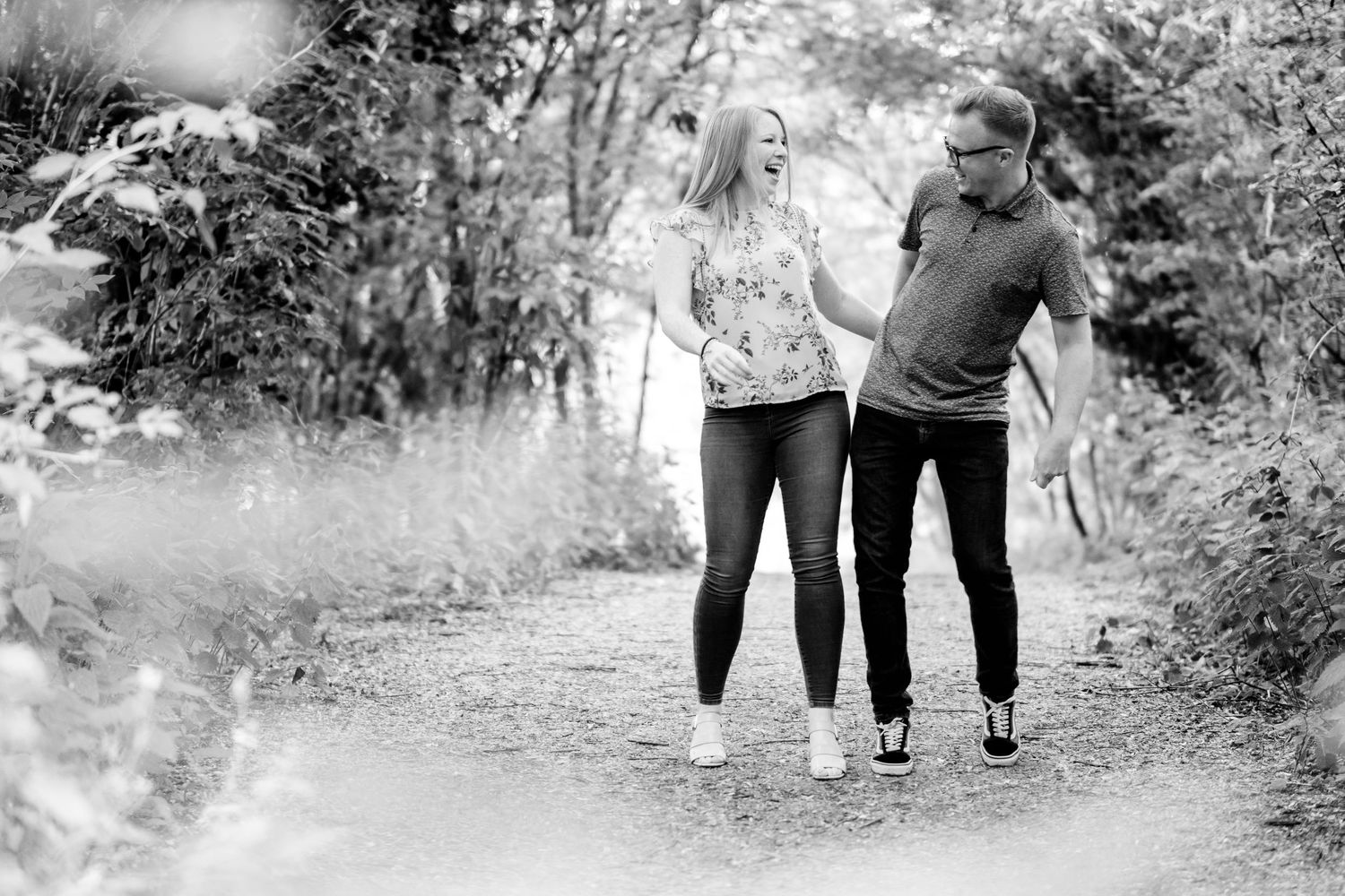 Black and white image shows couples walking together through natural outdoor setting.