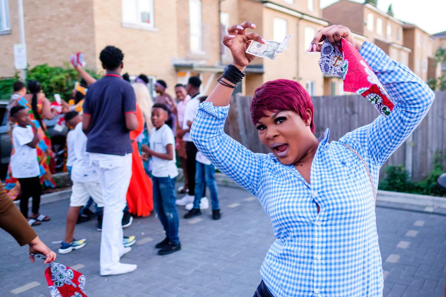 Cheerful outdoor celebration with people in blue checkered shirts raising their arms.