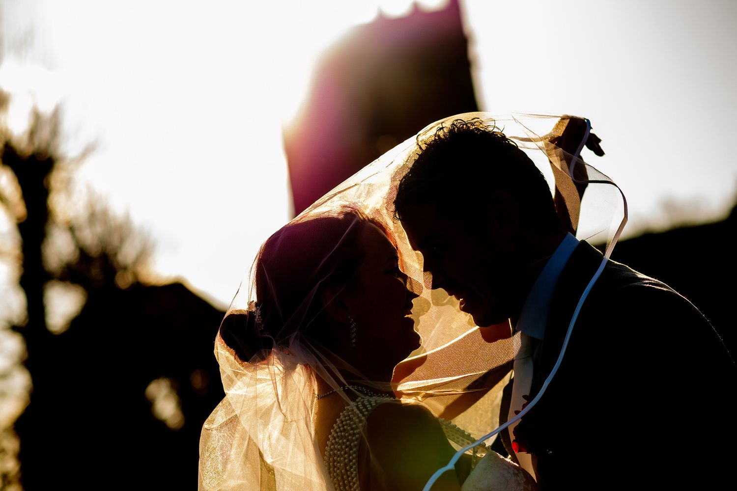 Silhouette of couple sharing romantic moment at sunset during wedding photoshoot.