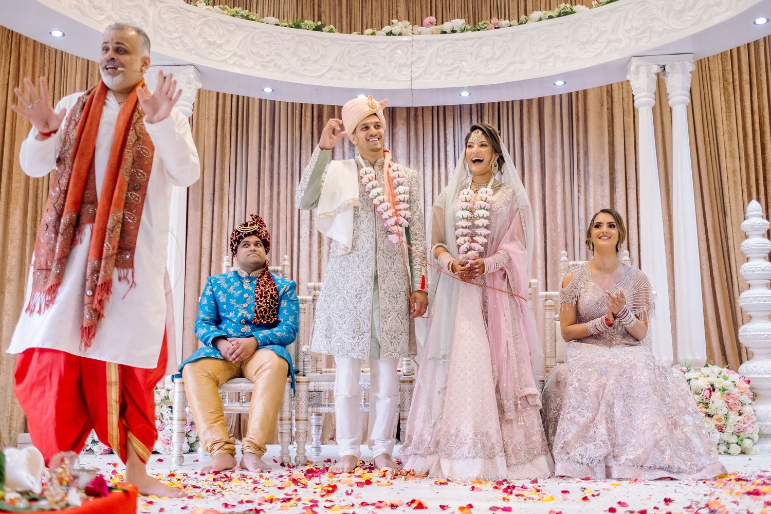 Wedding ceremony space decorated with white drapes and pink floral accents.