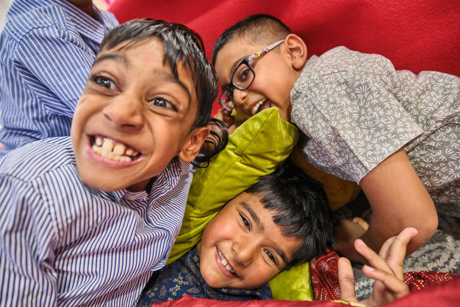 A sequence of four candid playful expressions and poses against a red background.