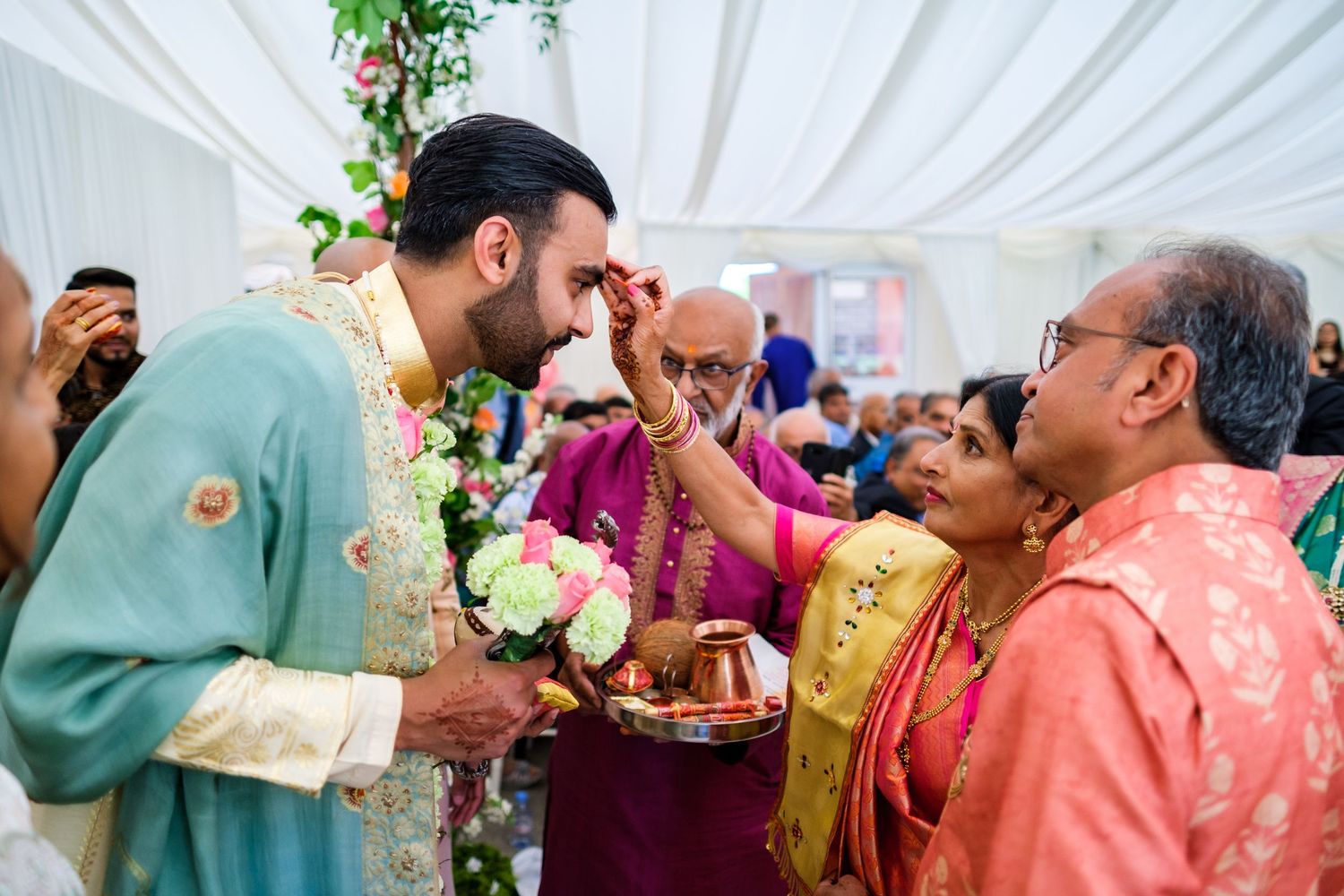 Traditional Indian wedding ceremony with blessing rituals under floral decorations.