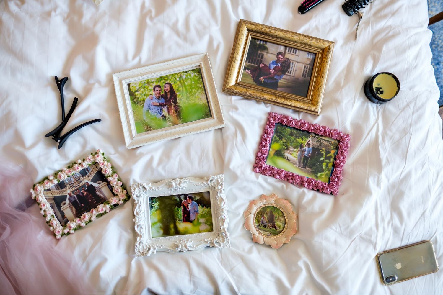 Collection of vintage photo frames and personal mementos scattered on white fabric surface.