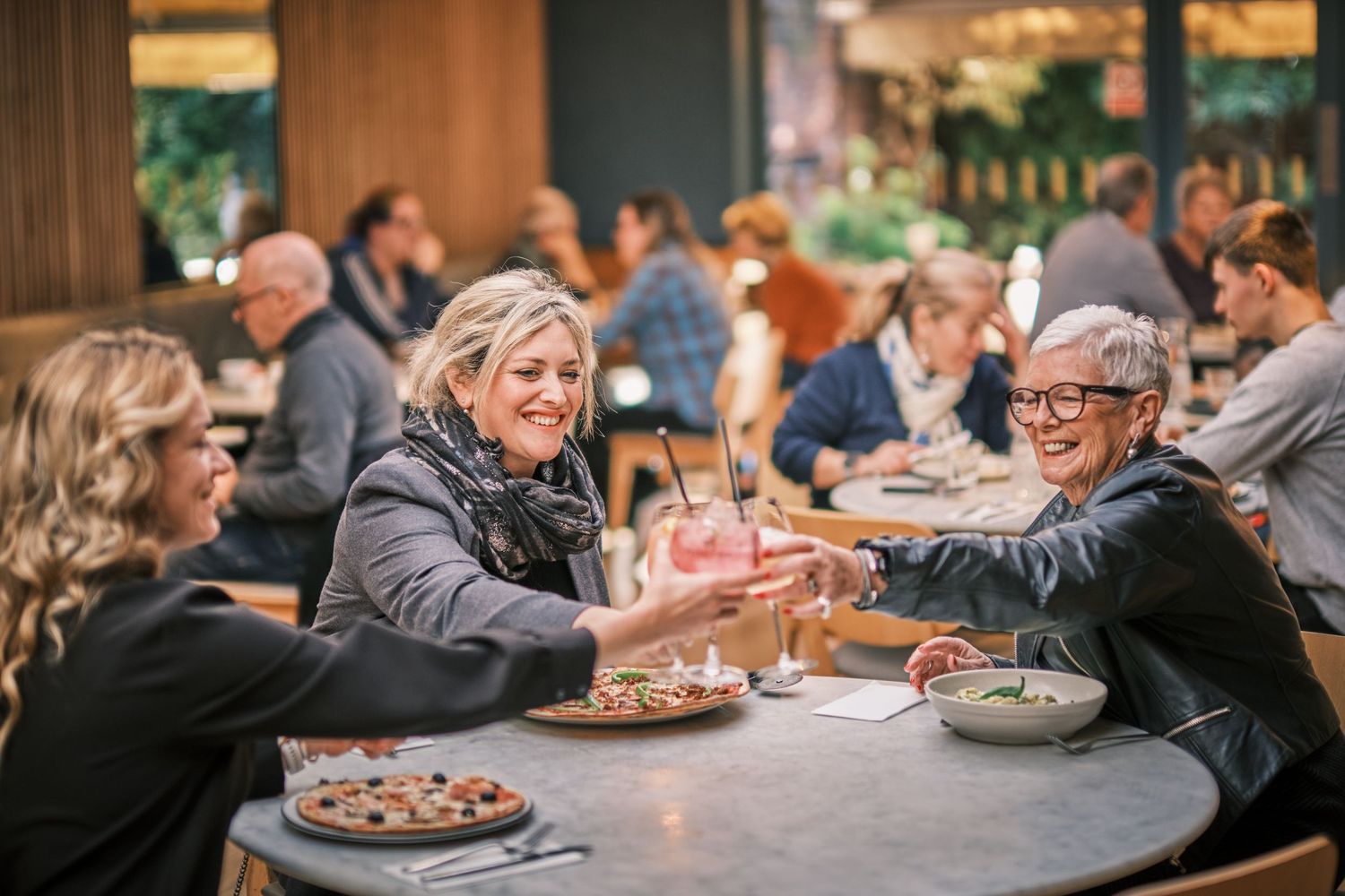 Restaurant guests gathered around round tables sharing meals in a casual dining environment.