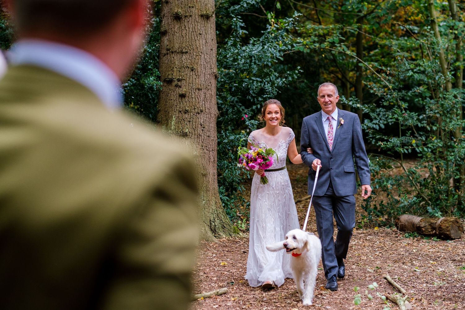 Wedding party walking through a lush forest path during an outdoor celebration.