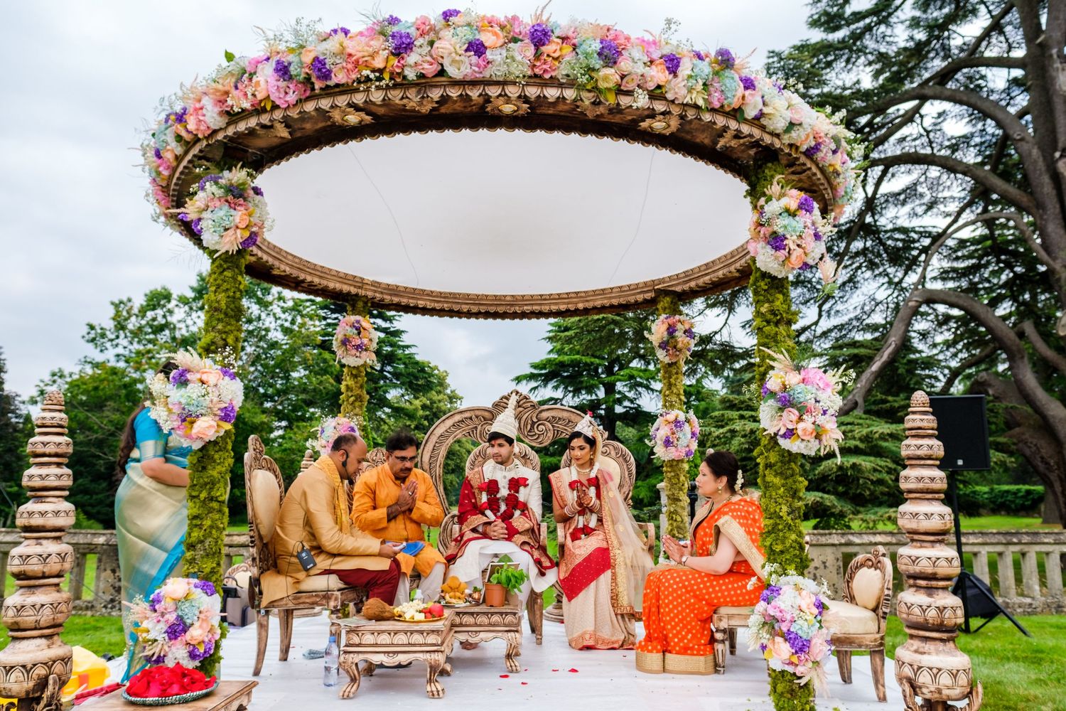 Traditional Indian wedding ceremony setup with floral mandap and decorative elements in an outdoor garden setting.