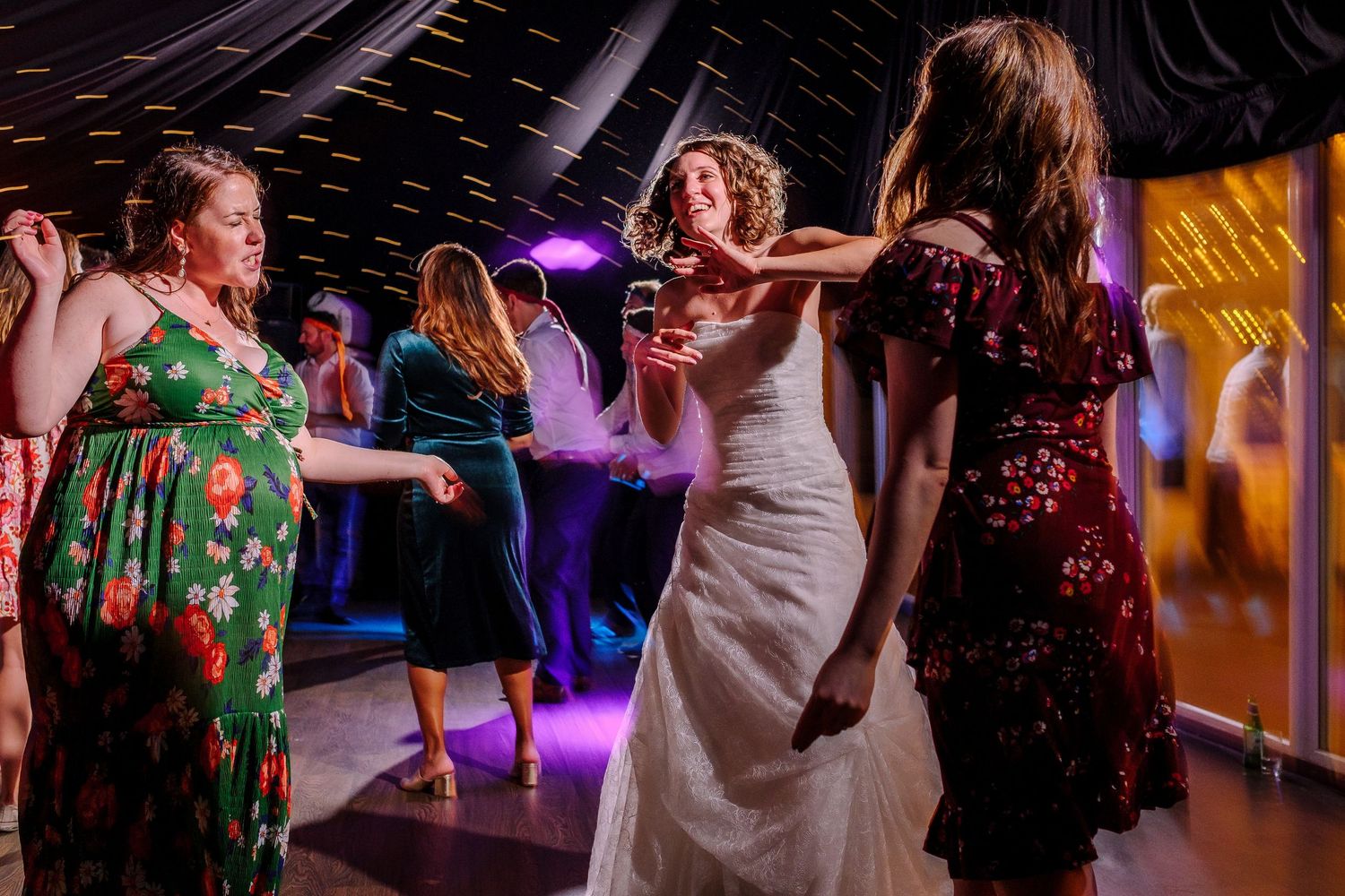 Wedding reception dance party with dramatic lighting and guests dancing.