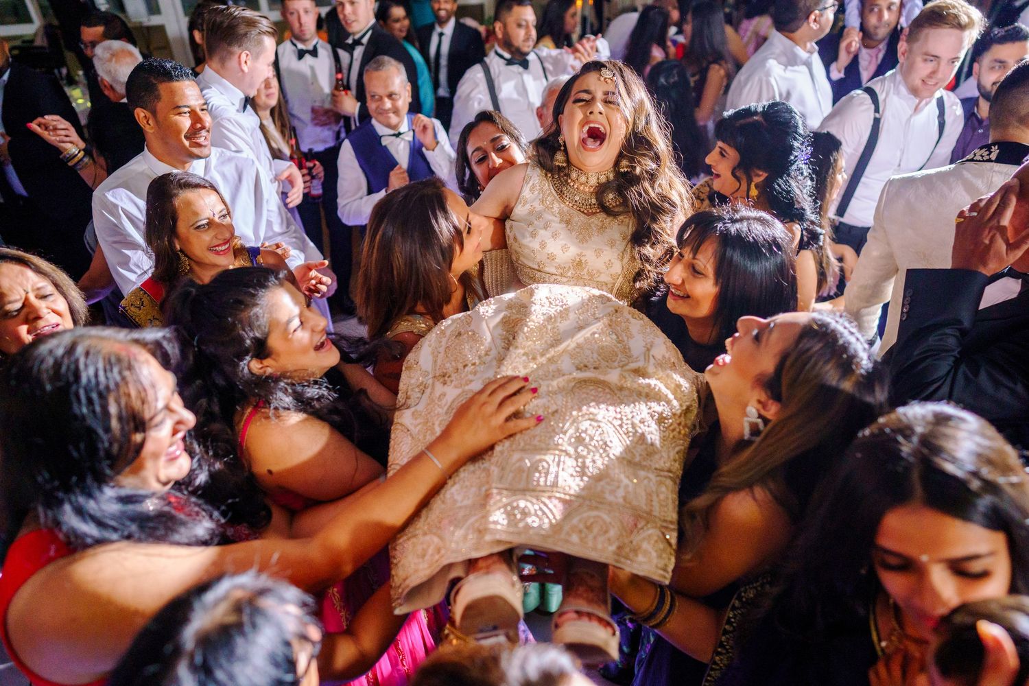 Energetic dance party at a wedding reception with guests celebrating on a crowded dance floor.