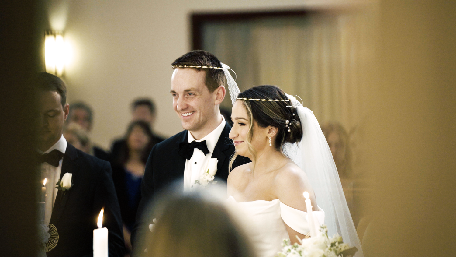 A couple shares an intimate moment during their wedding ceremony indoors with soft lighting.