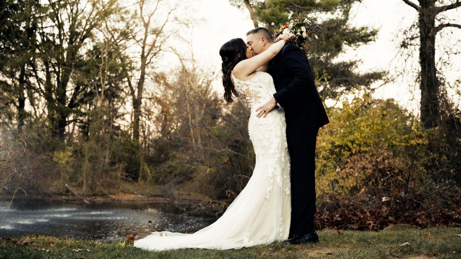 Sunset wedding portraits with newlyweds embracing near rustic wooden fence.