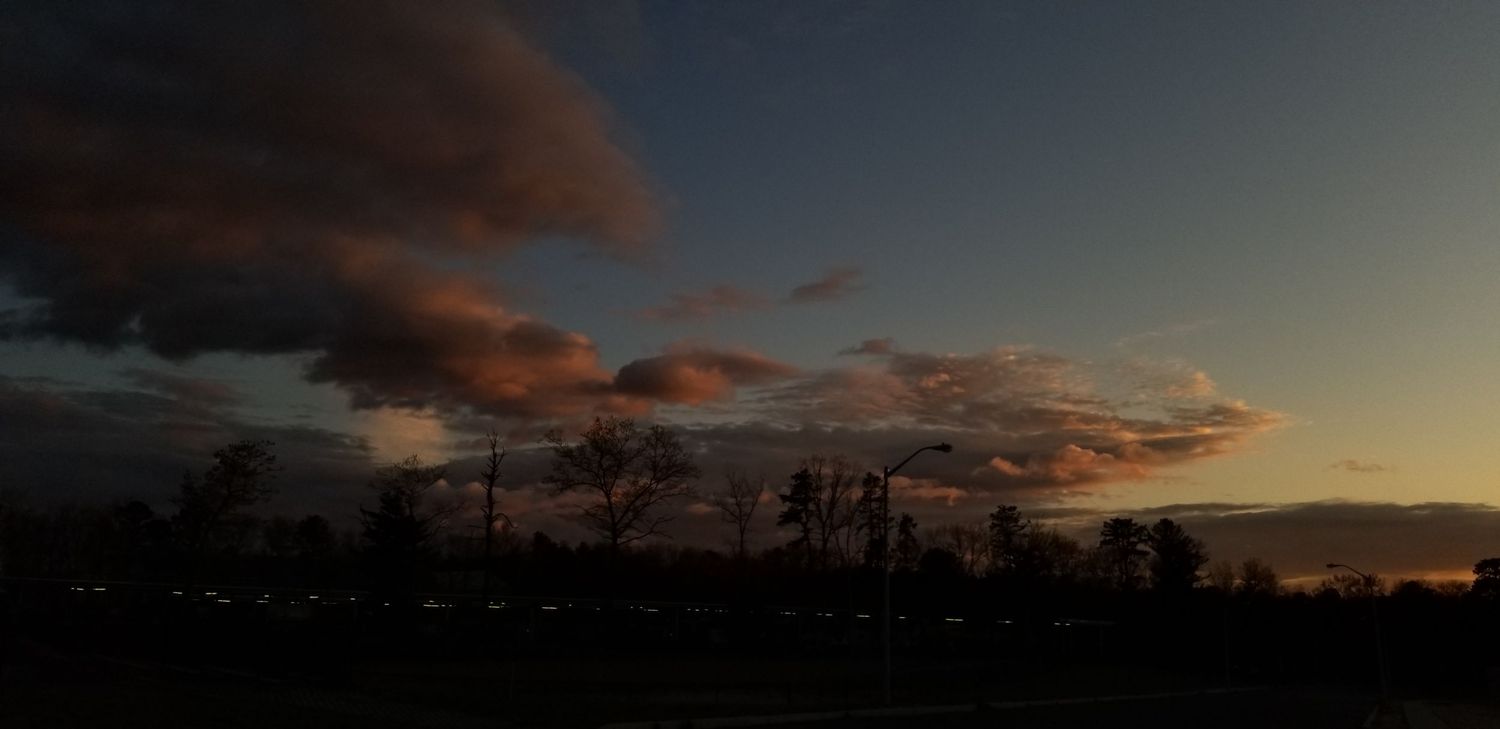 A dramatic sunset illuminates the horizon with deep orange and purple clouds stretching across the sky.