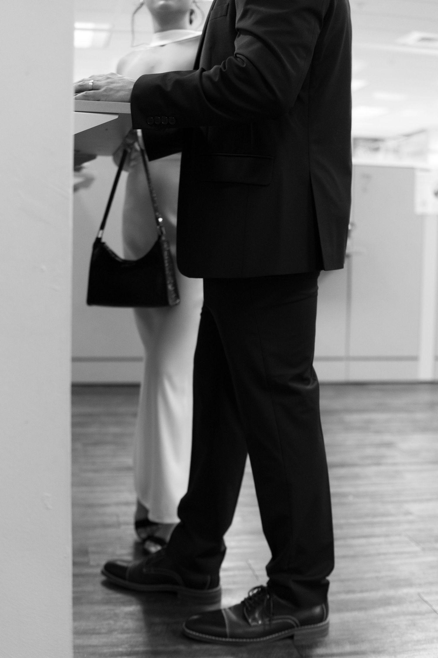 Black and white photo of couple in formal attire standing at a courthouse counter during civil ceremony.
