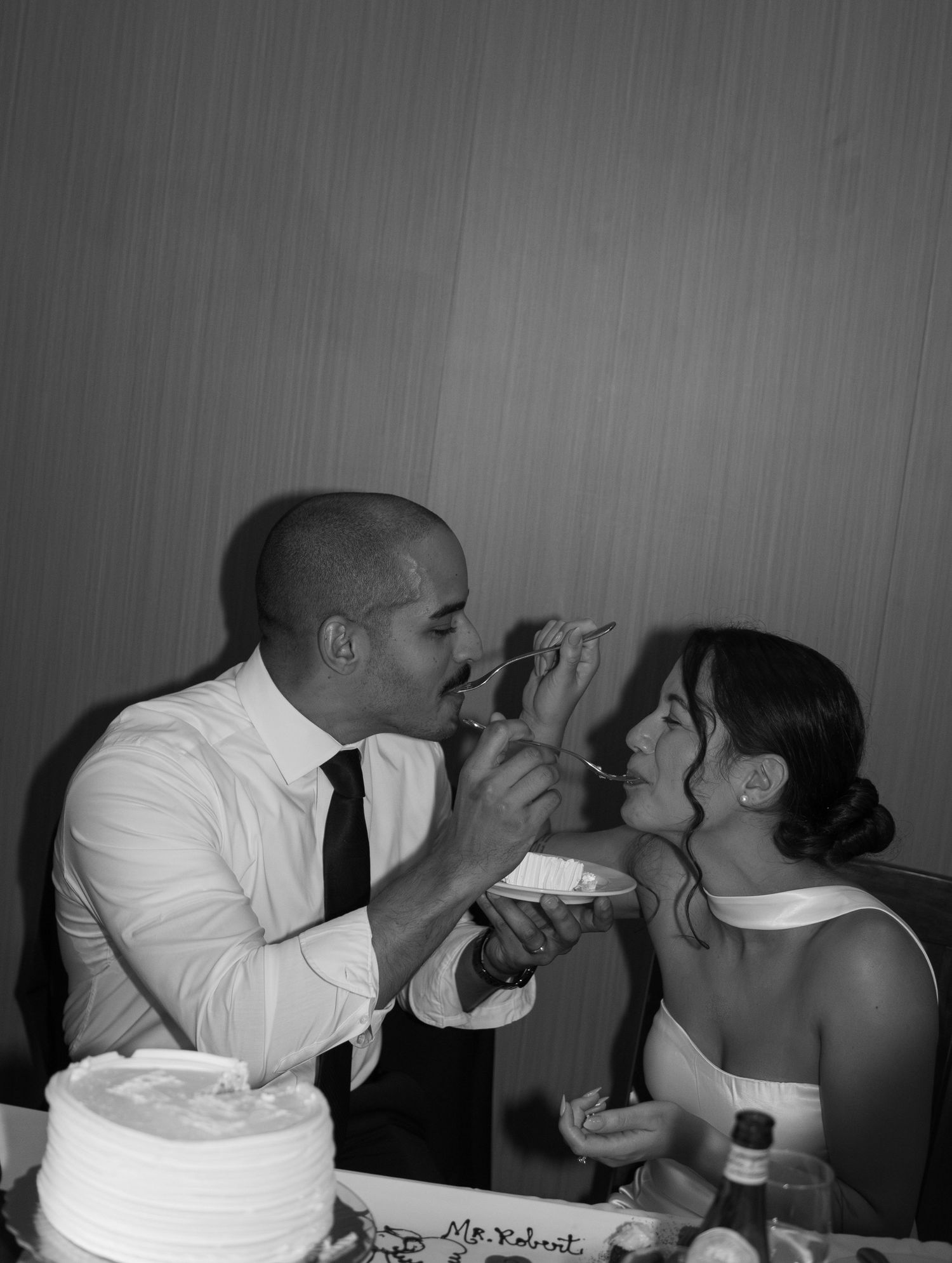 Black and white photo of bride and groom feeding each other wedding cake.