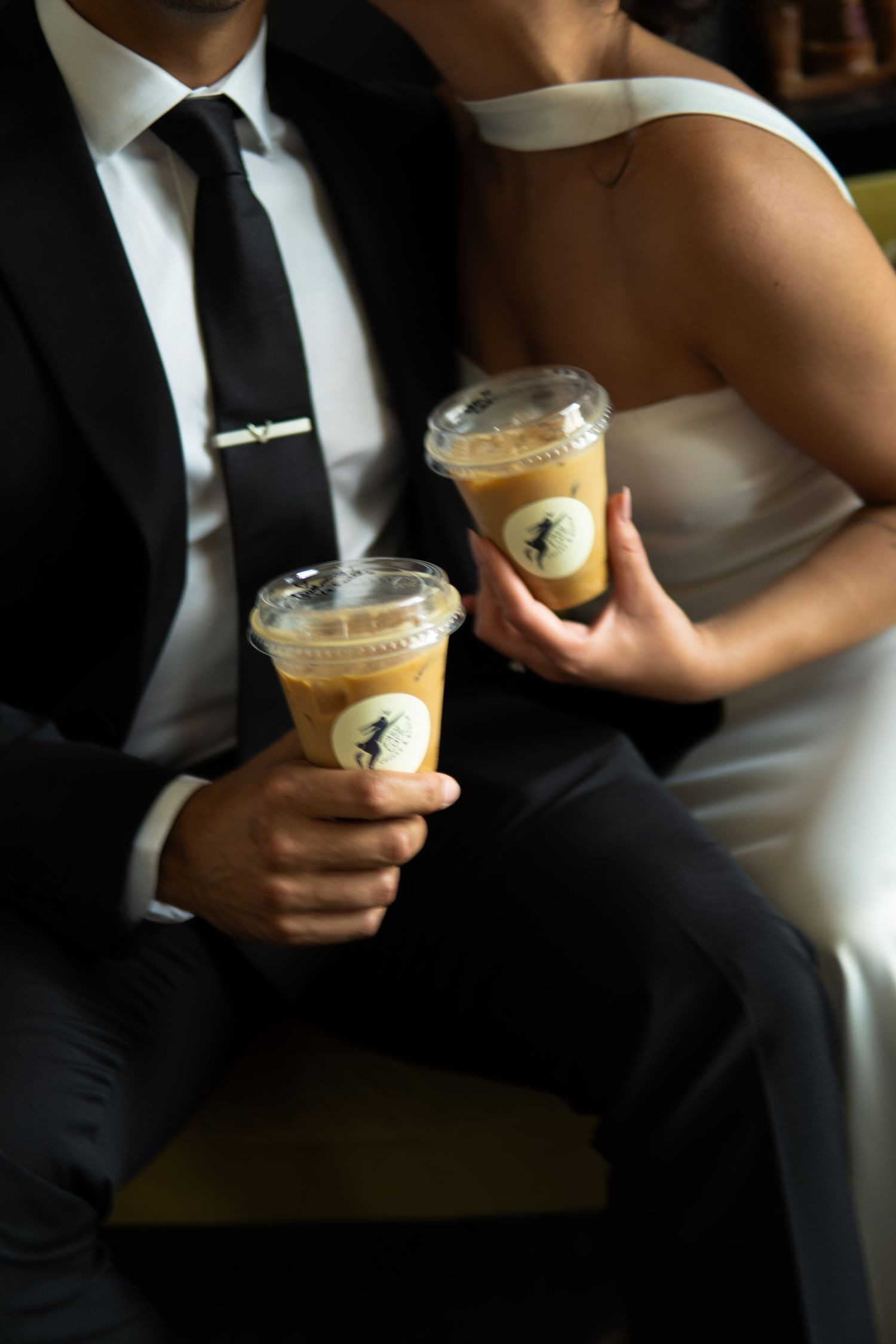 Bride and groom holding iced coffee drinks in clear cups at their wedding reception.