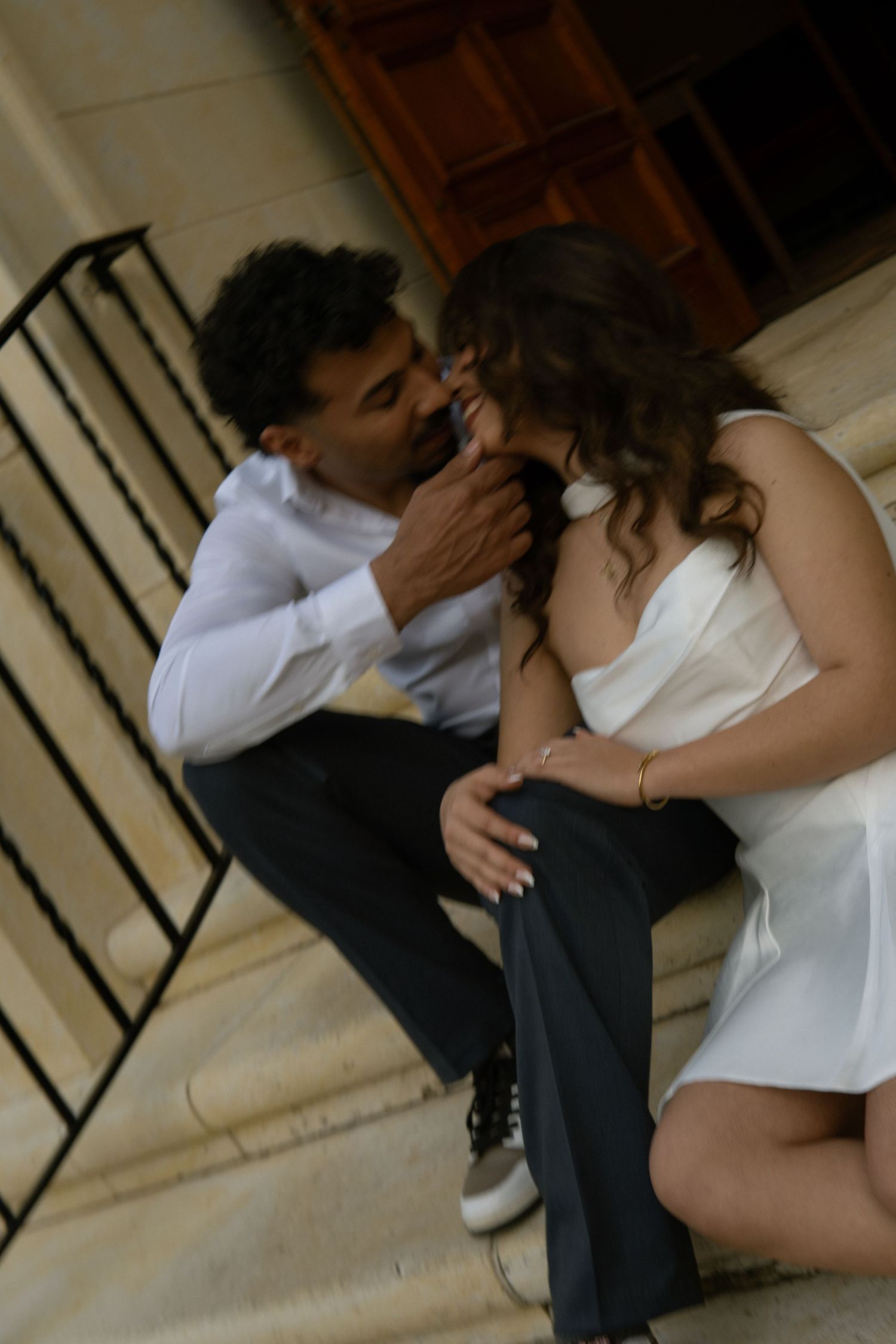 Romantic couple sharing an intimate moment on stone steps, man gently touching woman's face.