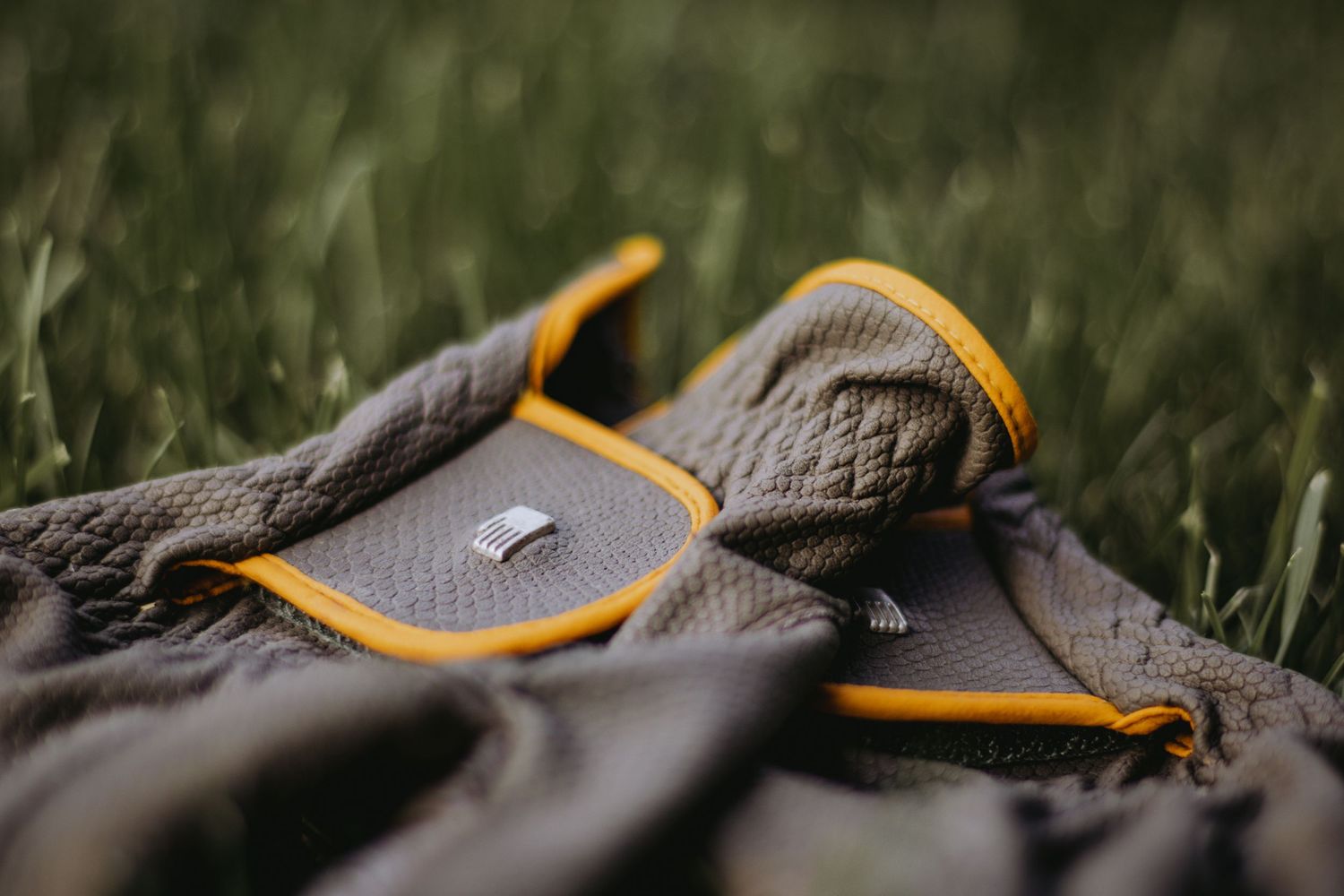 A close up view of the toe area of a brown leather hiking boot with orange laces against a grassy background.