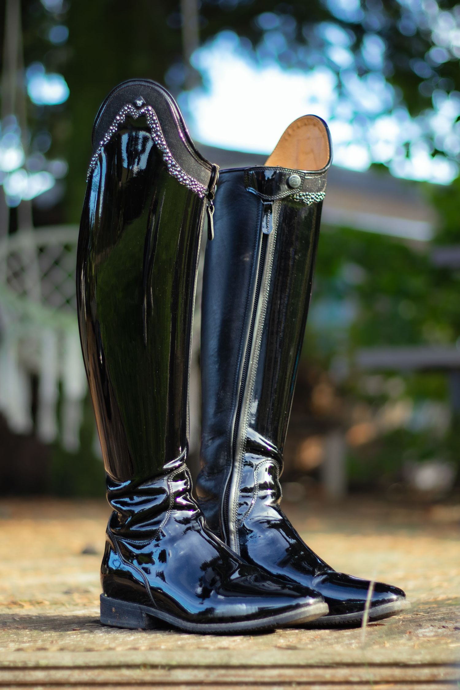 Shiny black equestrian riding boots displayed in a series of four identical photos on natural ground with blurred backgrounds.
