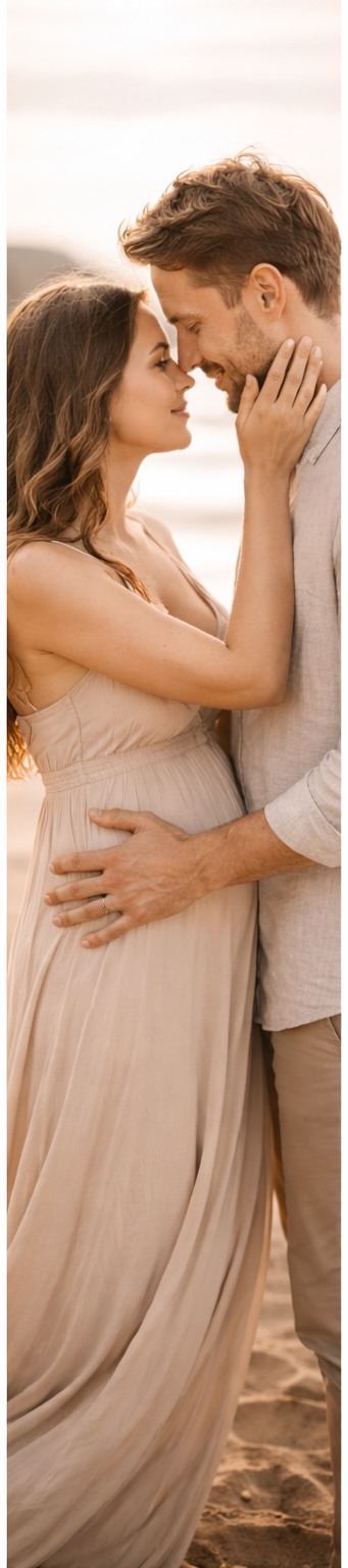 A romantic couple embraces on the beach at sunset, with her in a flowing blush dress and him in light casual attire.