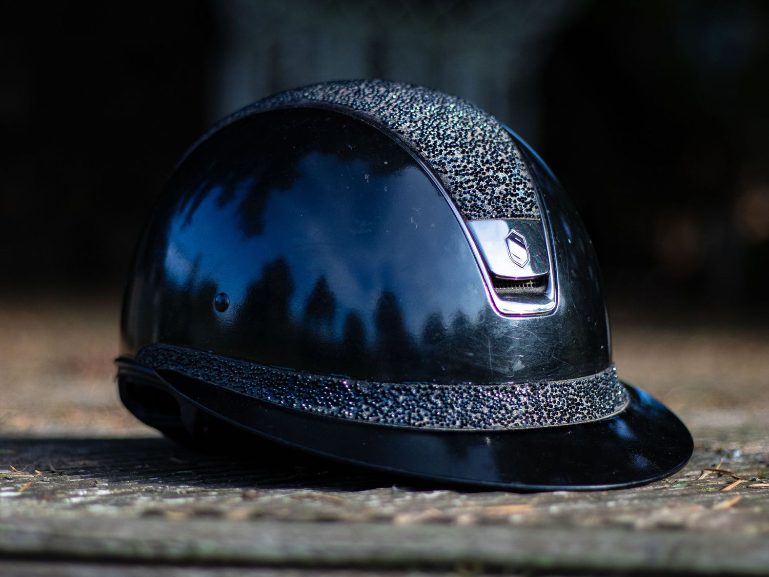 Various side views of a black bike helmet on a dark background with glitter details.