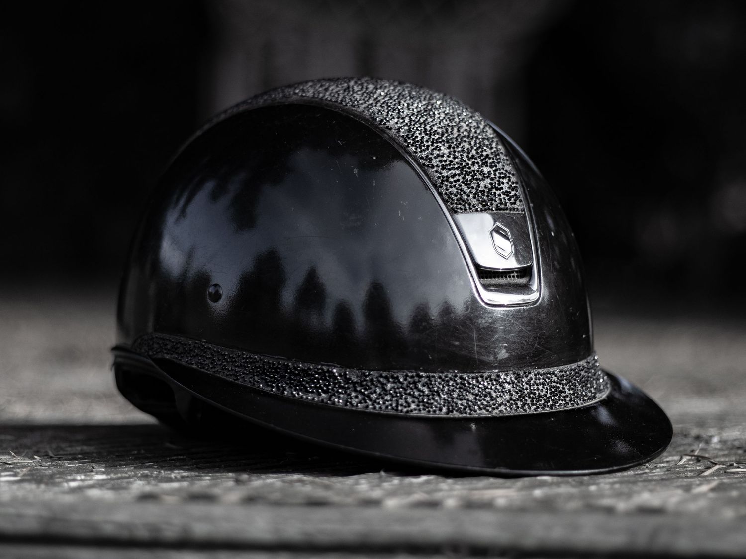 A line of black motorcycle or bicycle helmets arranged in a dark, moody composition showing different helmet profiles.