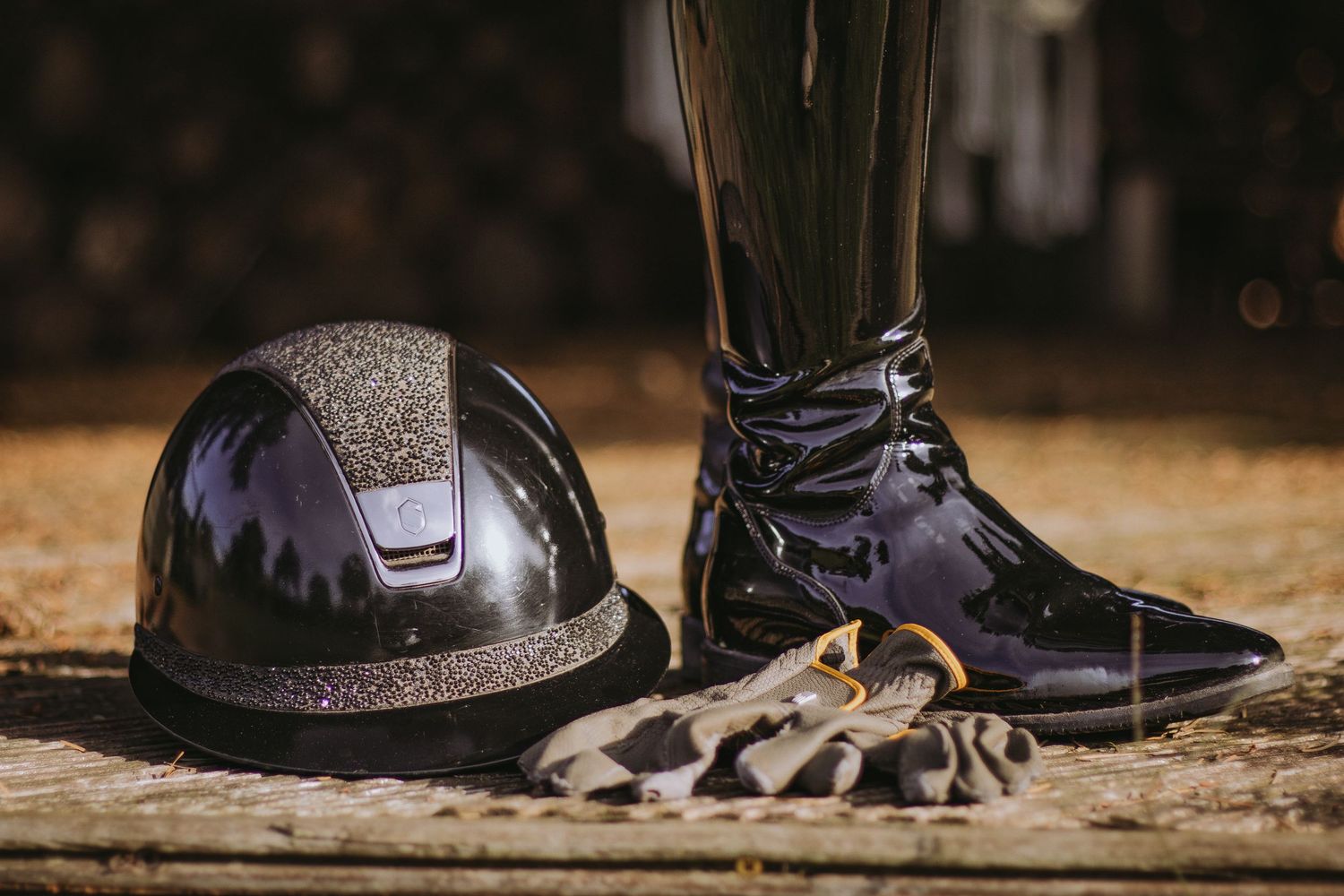Black leather riding boots with silver spurs lined up in a row against a rustic background.