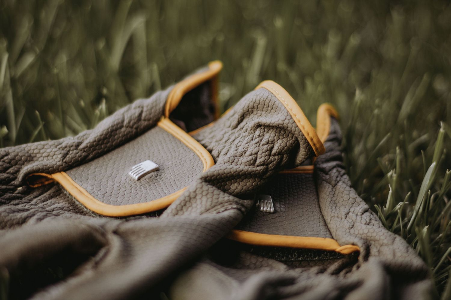 Close-up macro view of grey and orange athletic shoe on grass showing textural details and design elements.