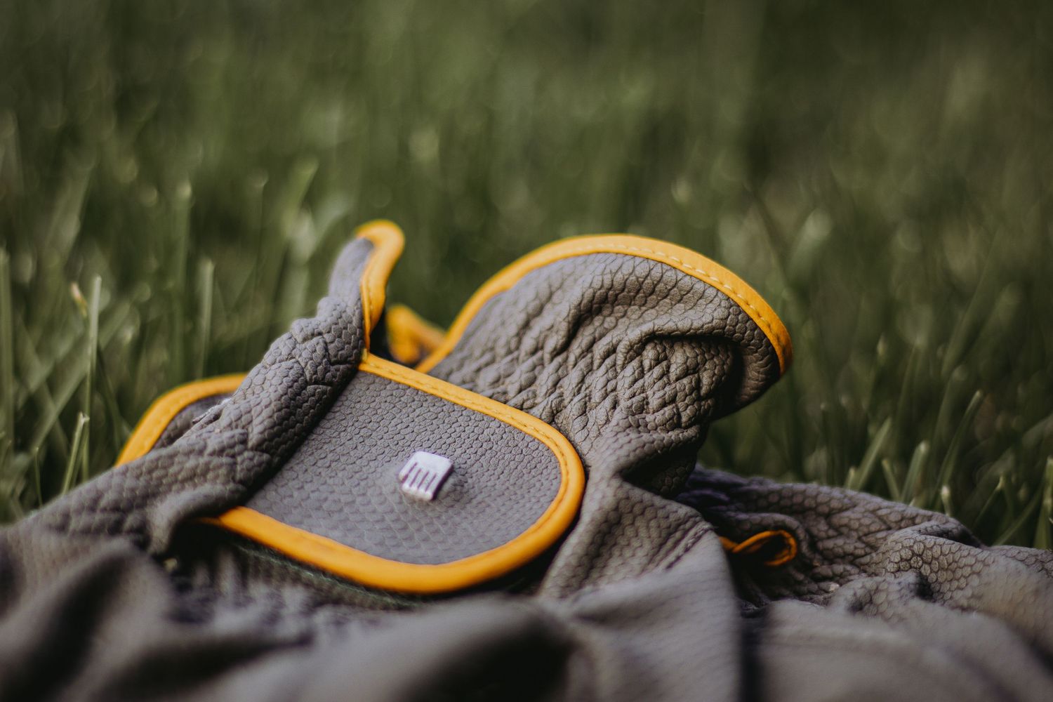 Close-up macro shot of a gray and yellow hiking boot lace detail against a blurred natural background.