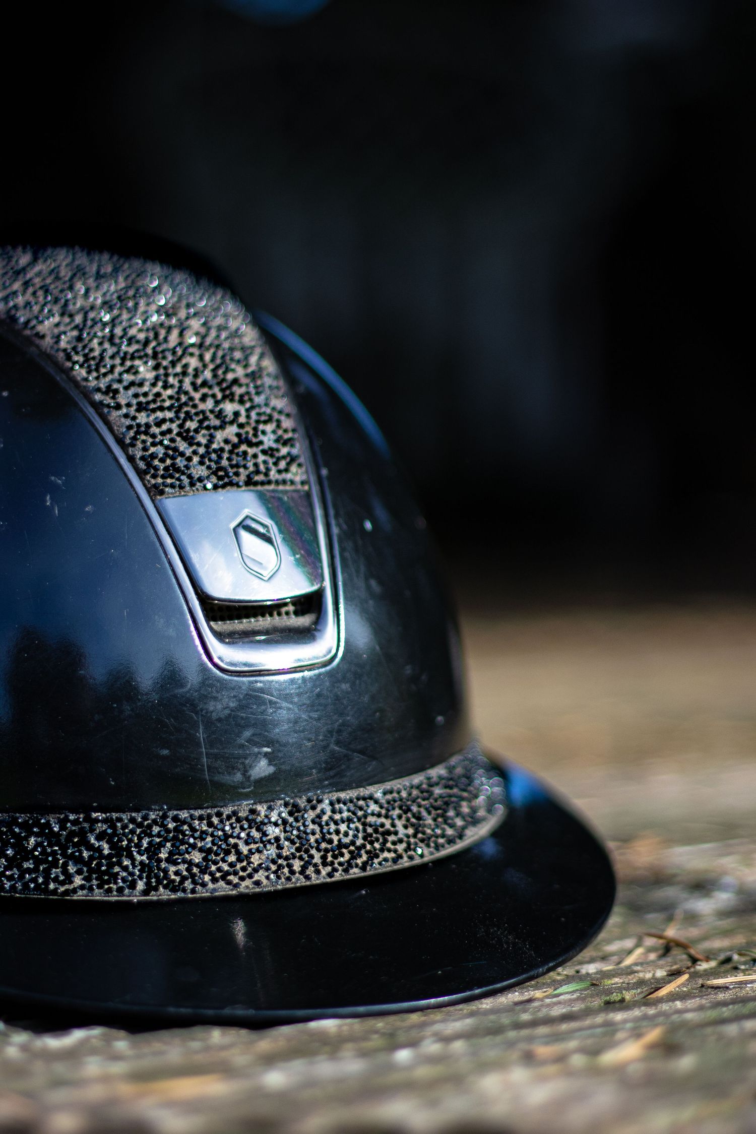 Close-up macro photography showing a series of detailed shots of a black equestrian riding helmet with water droplets.