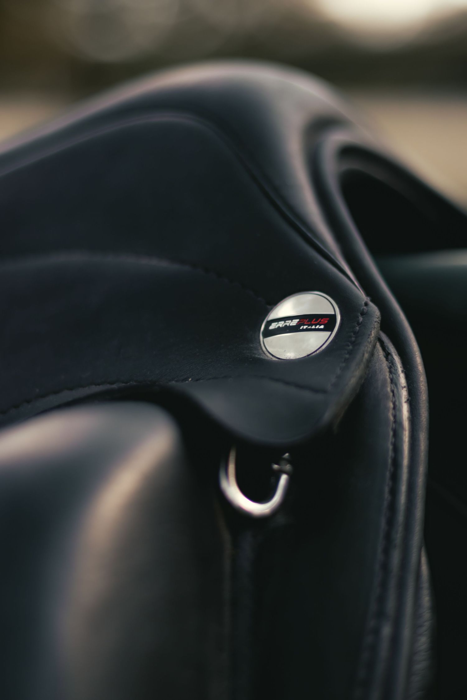 Close-up view of black leather motorcycle gear straps and details with metallic hardware in soft lighting.