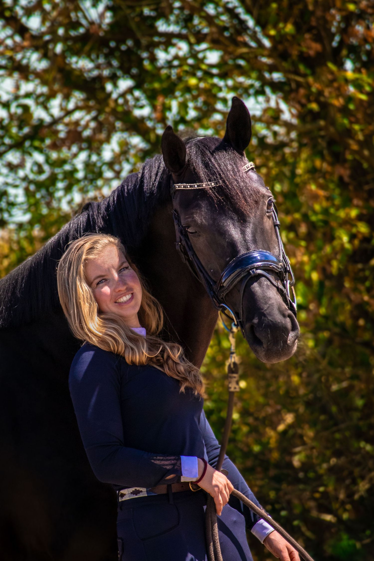 A series of intimate portrait shots showing a gentle embrace between a person in navy blue and a black horse in autumn.