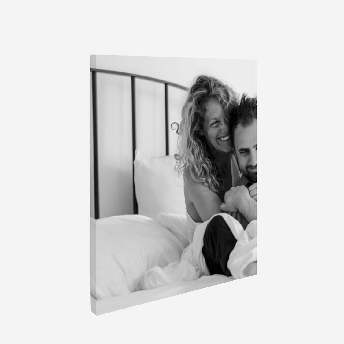 Black and white photo of smiling people in an intimate moment in bed.